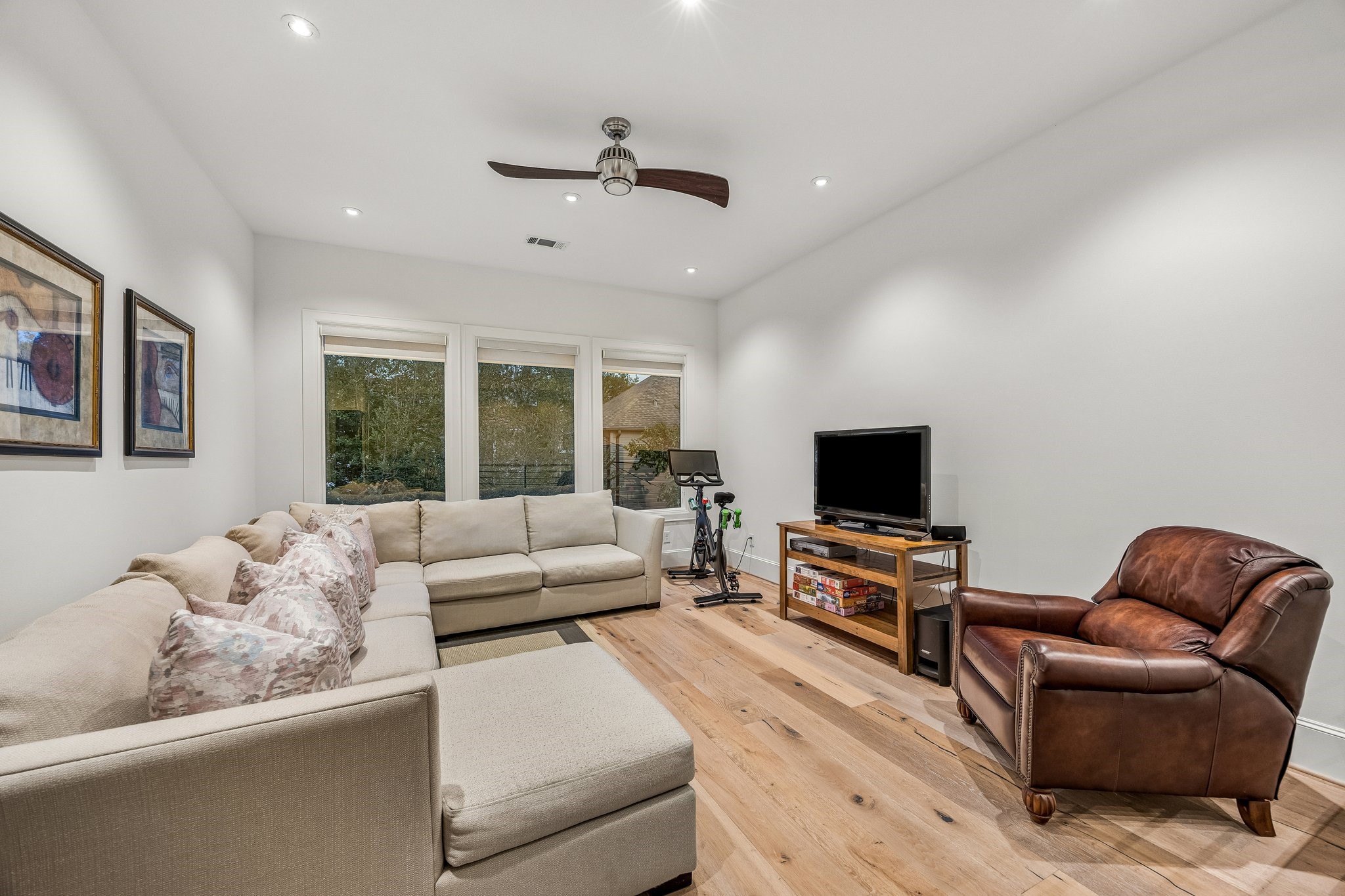Second Floor Media Room with LED recessed lighting, wide plank floors, 8 Inch baseboards, Linear ceiling fan, and window treatments.