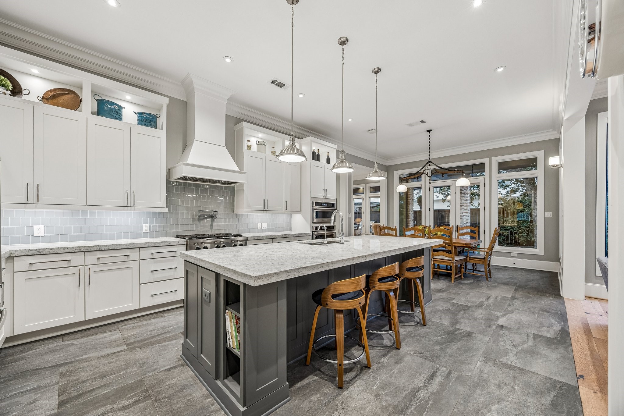 Rich charcoal-toned tile flooring provides a beautiful contrast to the Classic Carrara Stone Counters and the grey/blue toned subway tile backsplash.