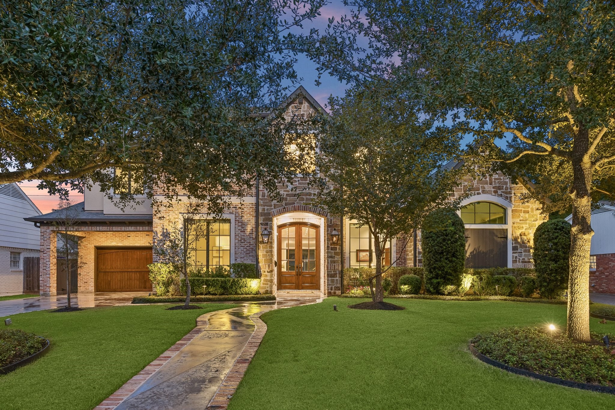 Nestled beneath a magnificent canopy of mature oak trees, this exquisite residence showcases timeless architecture, exceptional curb appeal, and refined elegance. A beautiful combination of natural stone and brick creates a rich, textured exterior, complemented by striking rooflines, graceful arches, and thoughtfully designed architectural details.
