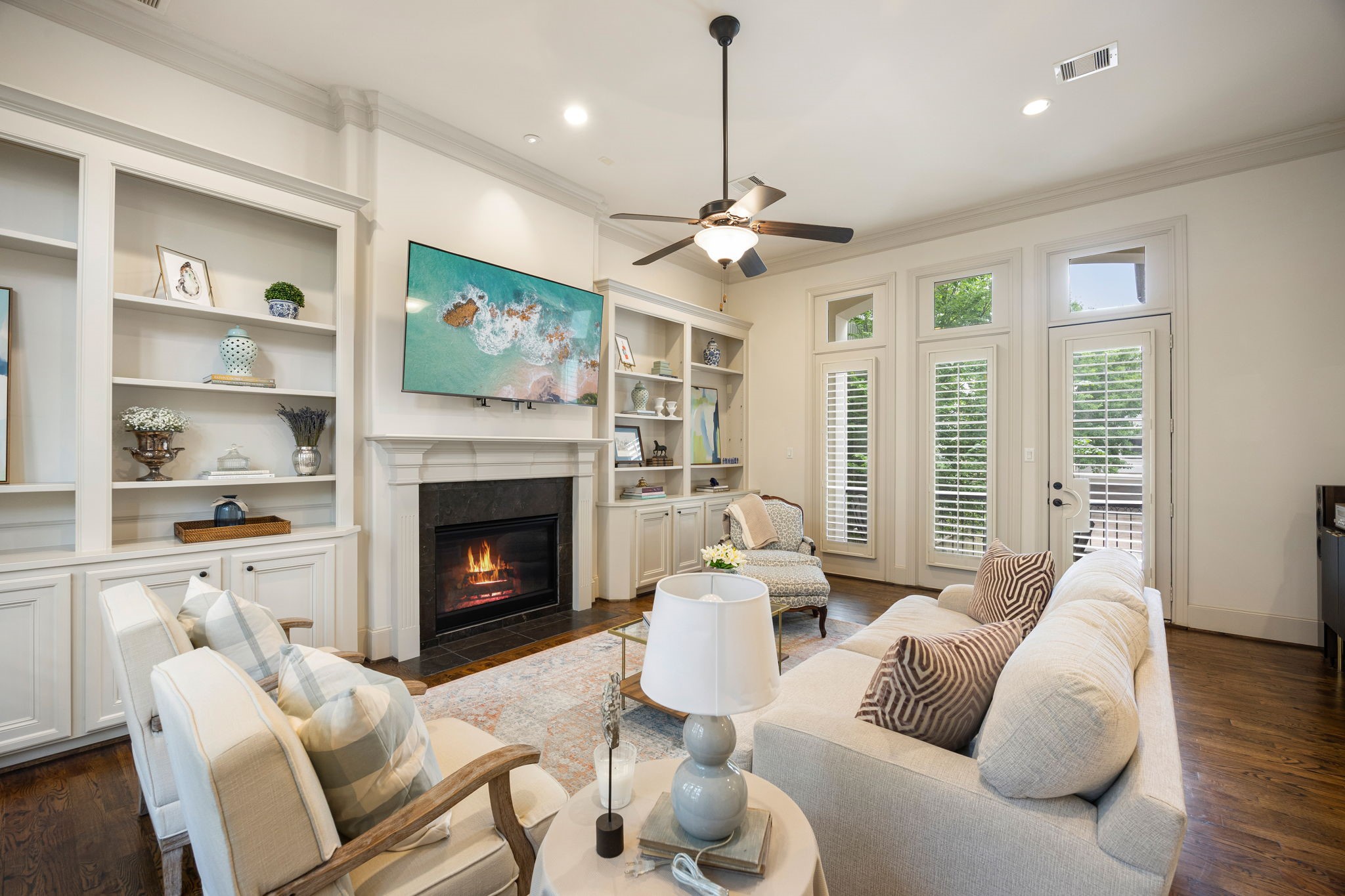 The 2nd floor living room is inviting and features an elegant fireplace, built-in shelving, and beautiful hard wood floors. The French doors lead to an outdoor balcony with views of the lush courtyard below.