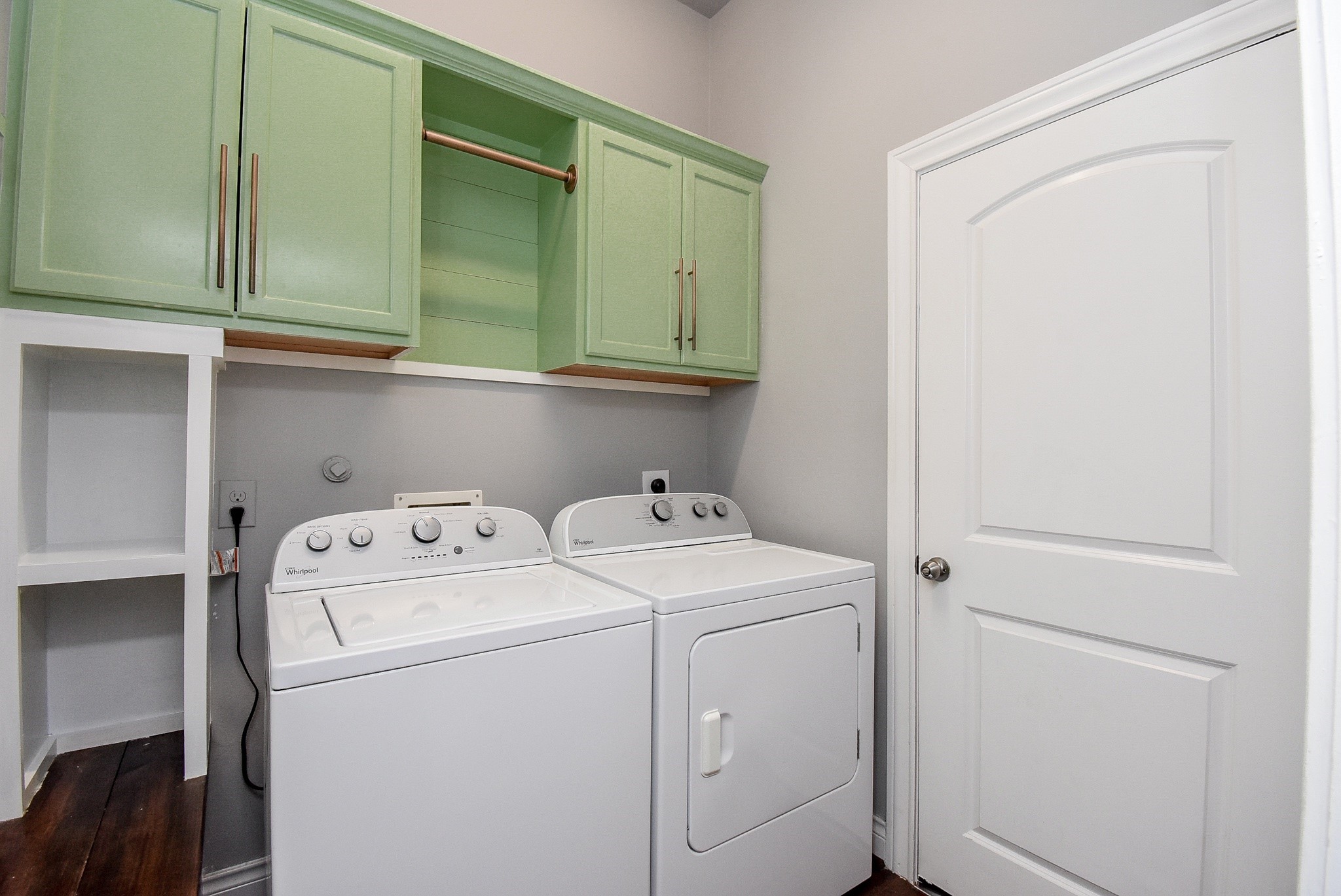 The well-appointed utility room offers upper cabinetry, open shelving, and a convenient hanging rod, providing exceptional storage and organization to make everyday chores simple and efficient.