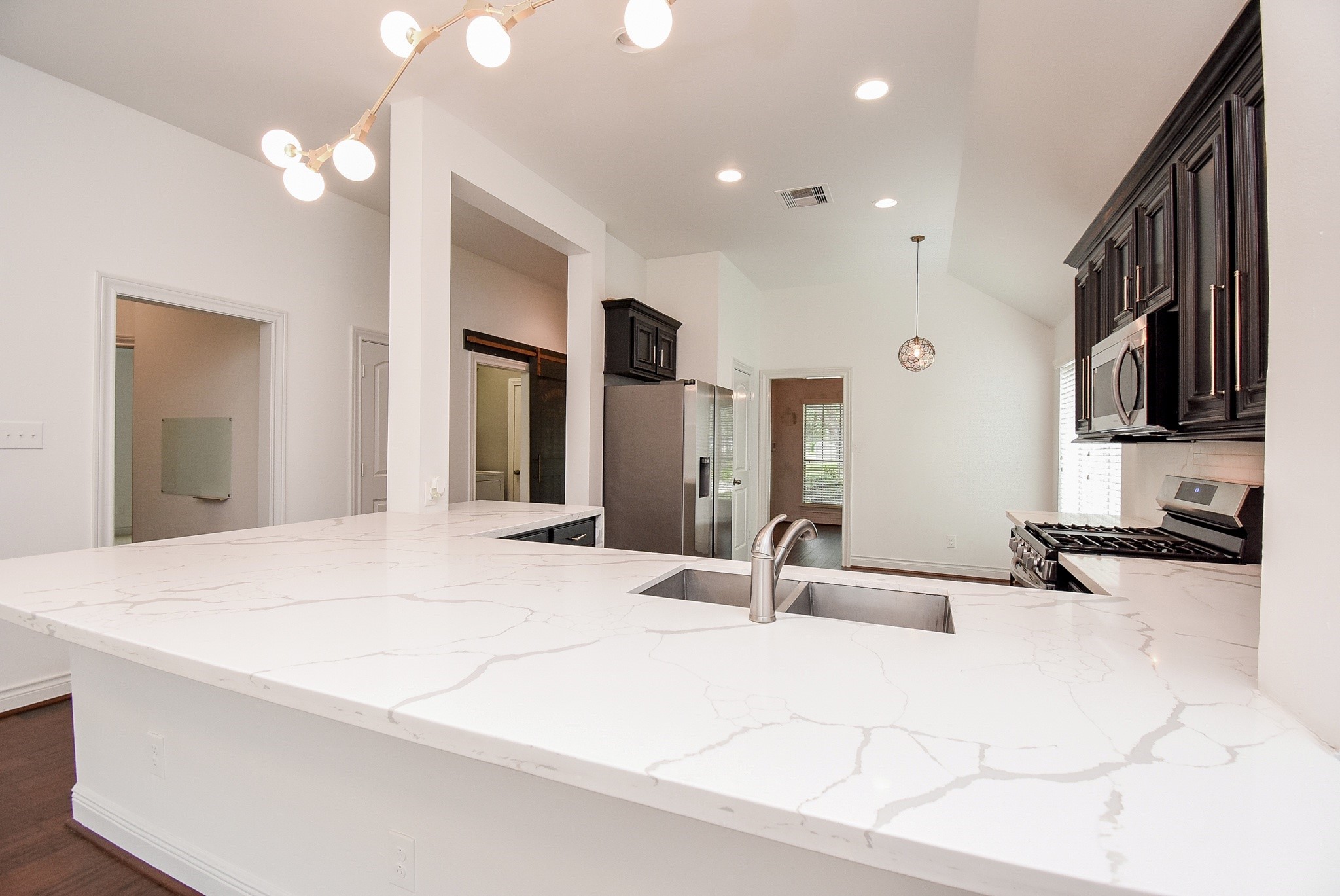 The expansive quartz island is the centerpiece of this beautifully designed kitchen, combining generous workspace, a built-in sink, and an inviting setting for gathering with family and friends. The open-concept layout enhances both functionality and everyday comfort.
