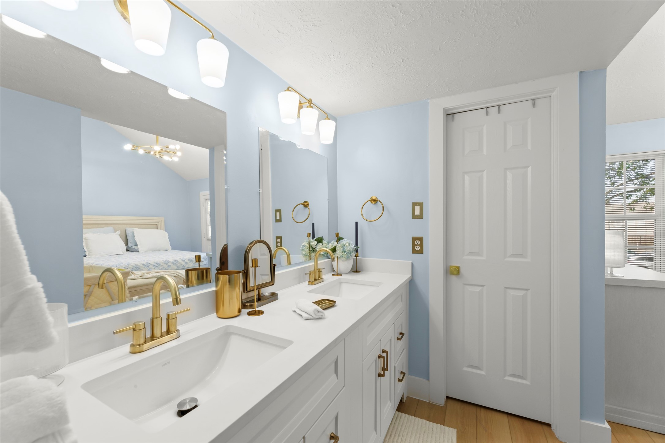 Sleek and modern bathroom featuring a double vanity with elegant gold fixtures, complemented by soft lighting and a spacious walk-in shower for a touch of luxury.
