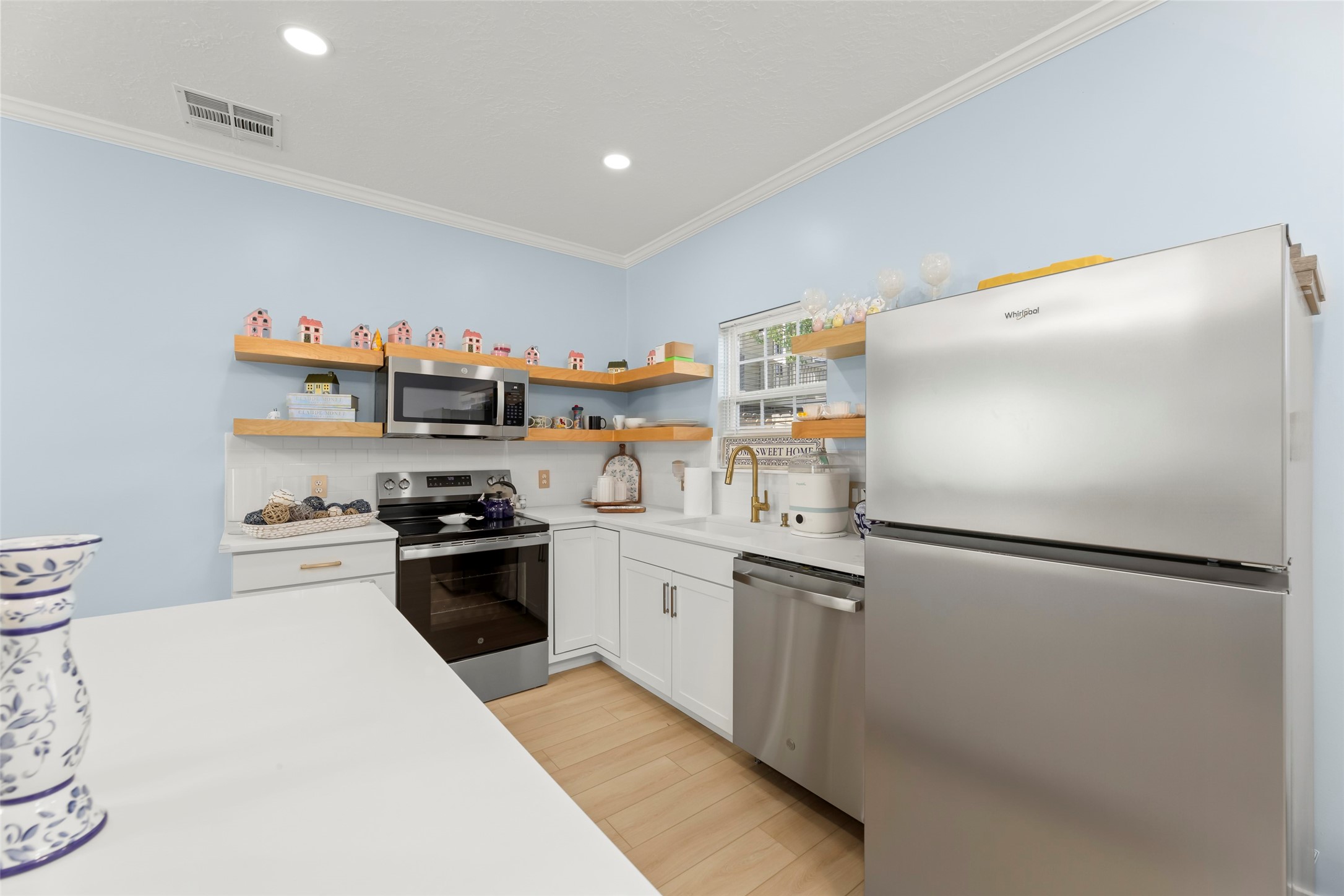 Charming open-plan living area with light wood flooring, a modern kitchen, and a cozy sitting space, complemented by a stylish staircase leading to the upper level.