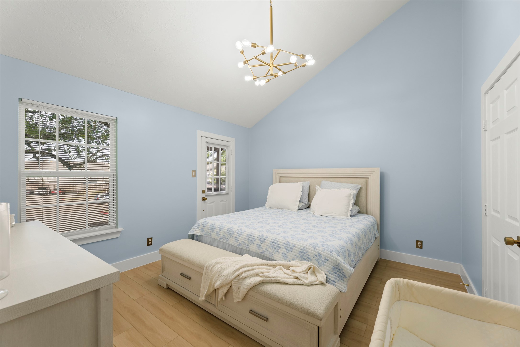 Experience the serene charm of this family room, where soft blue walls and a vaulted ceiling create an inviting sanctuary, complete with elegant lighting and a seamless flow to a private ensuite.
