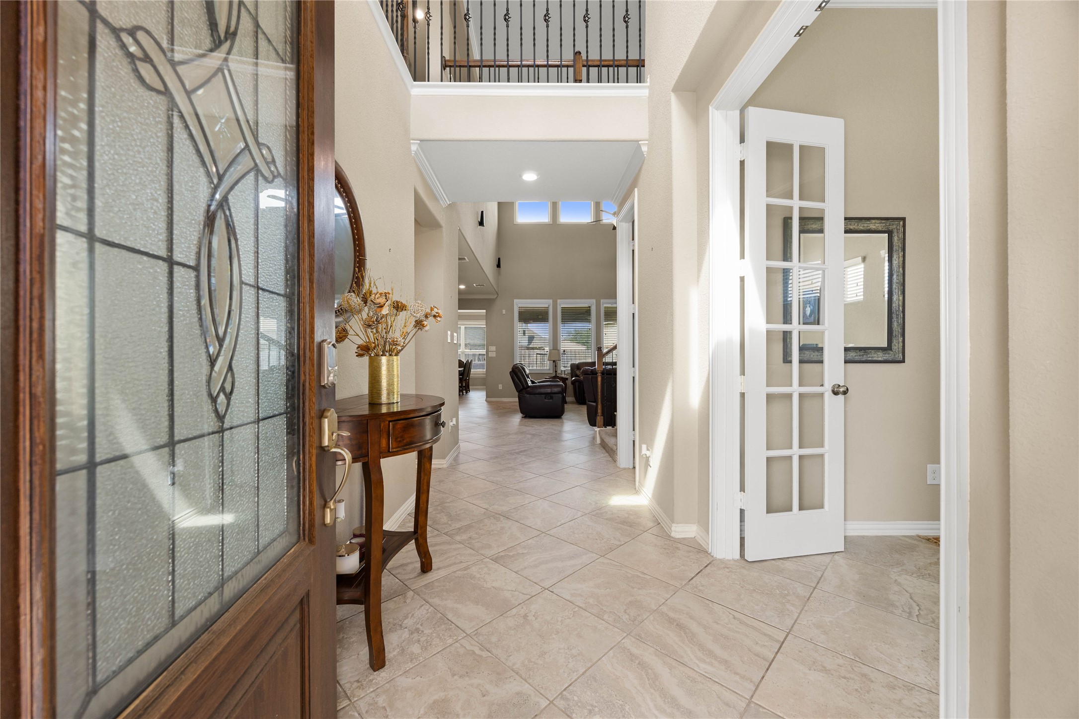 Elegant entryway with tiled floors, high ceilings, and abundant natural light, leading to a spacious living area. French doors open to a versatile room, perfect for an office or study.