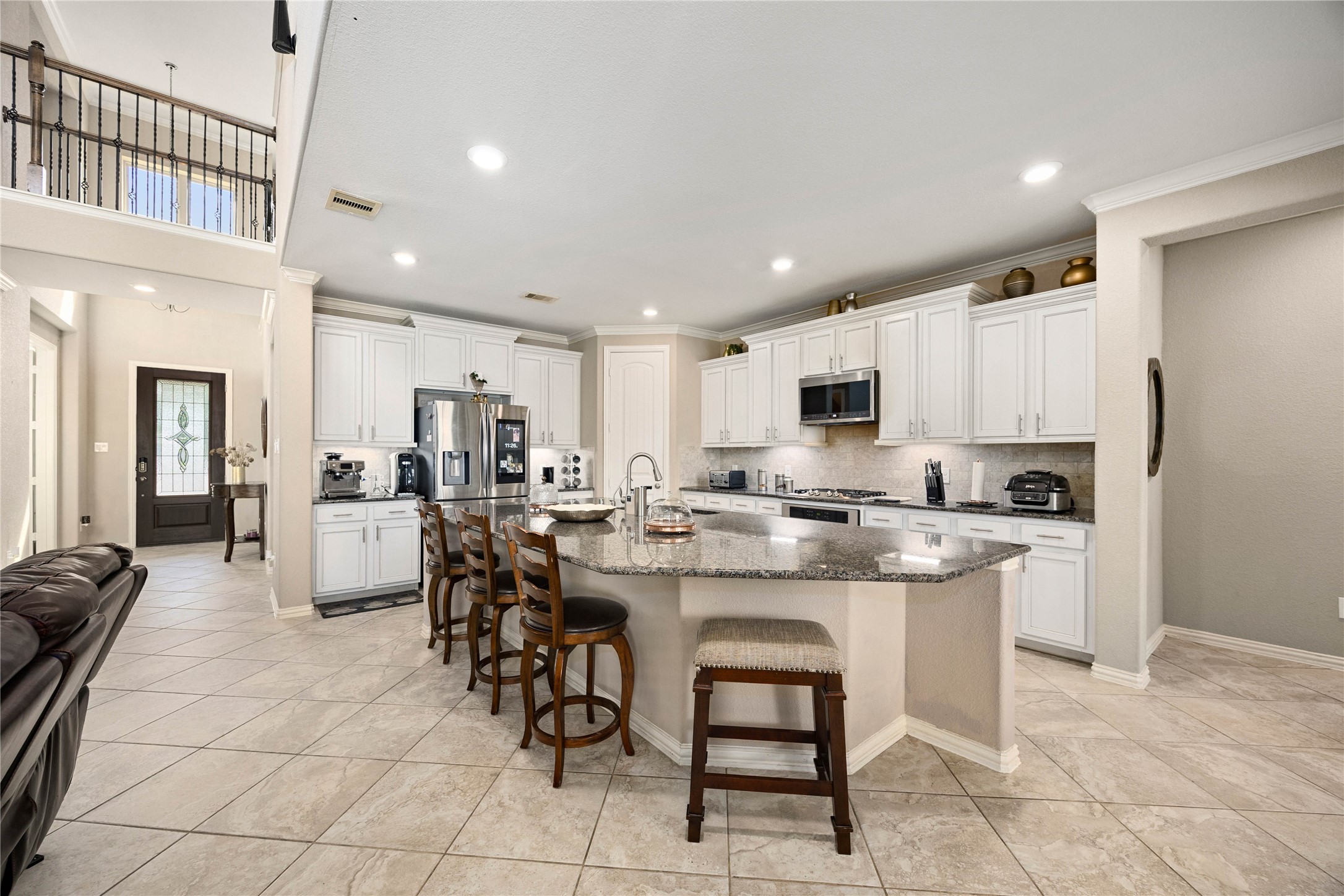 Spacious kitchen with modern stainless steel appliances, elegant granite countertops, and ample white cabinetry. An inviting island with seating is perfect for casual dining and entertaining.