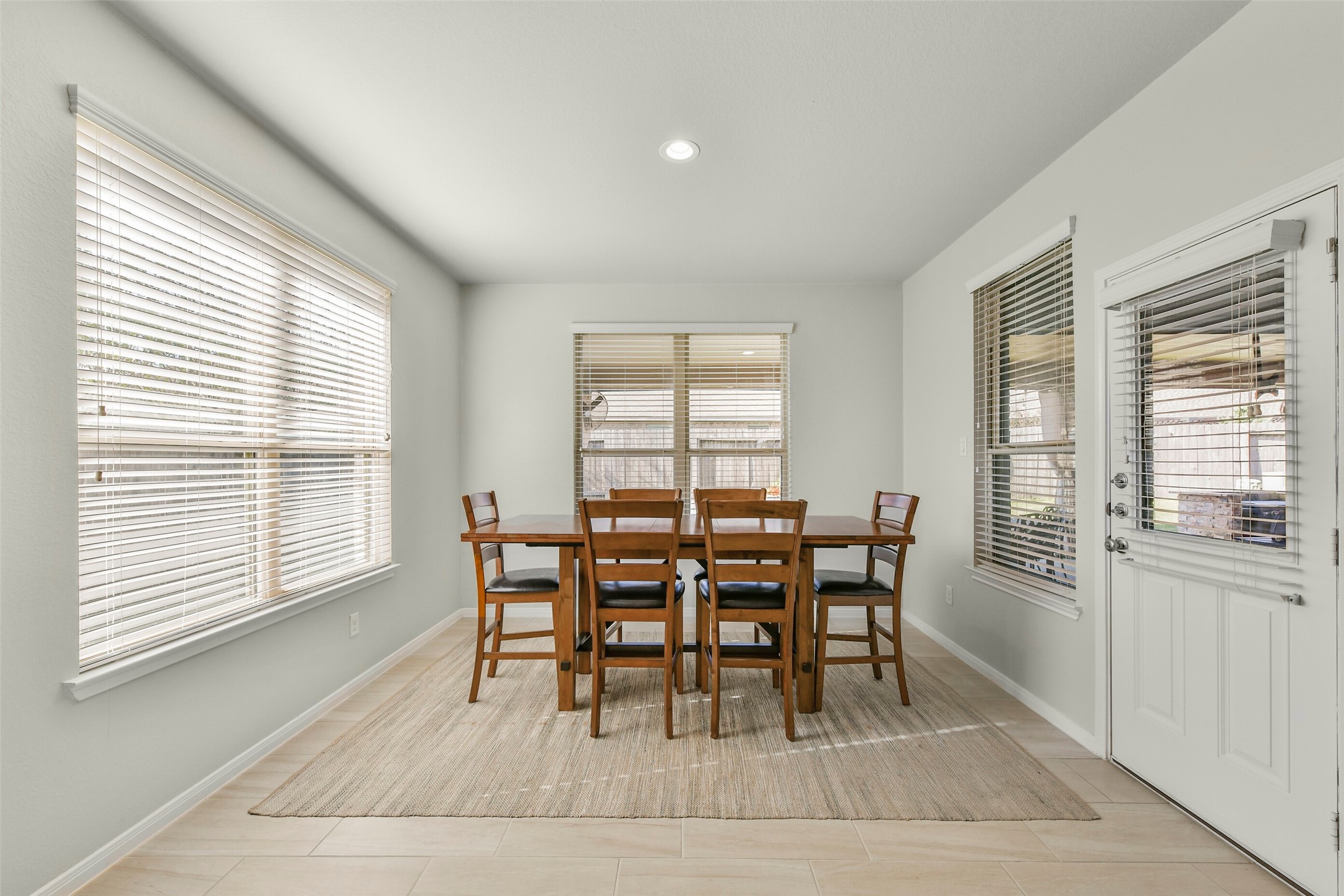 Large breakfast area/ dining room with tile floors opens to back patio