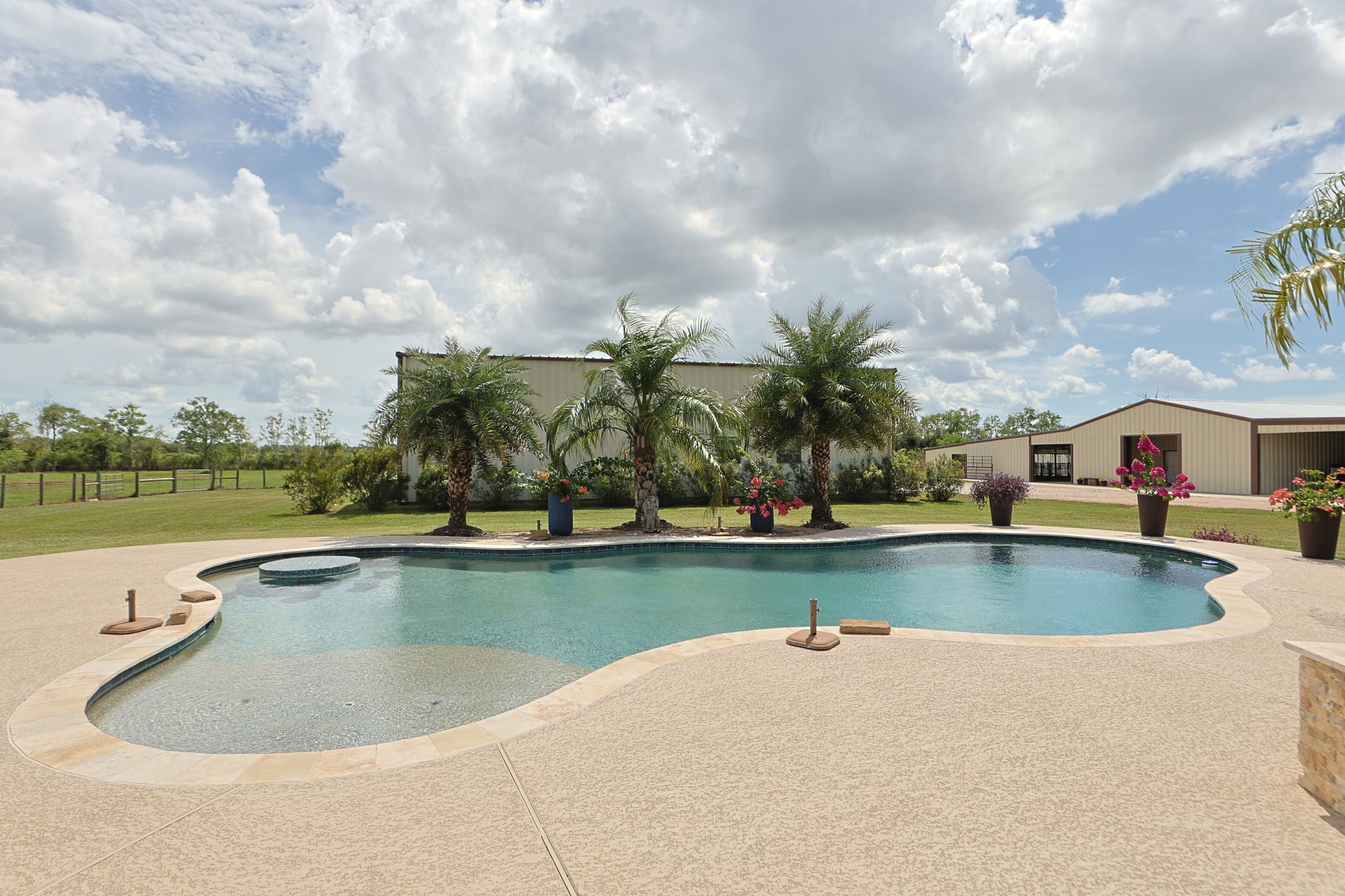Experience serene outdoor living with a sparkling pool surrounded by lush palm trees and beautifully landscaped grounds, perfect for relaxation and entertaining.