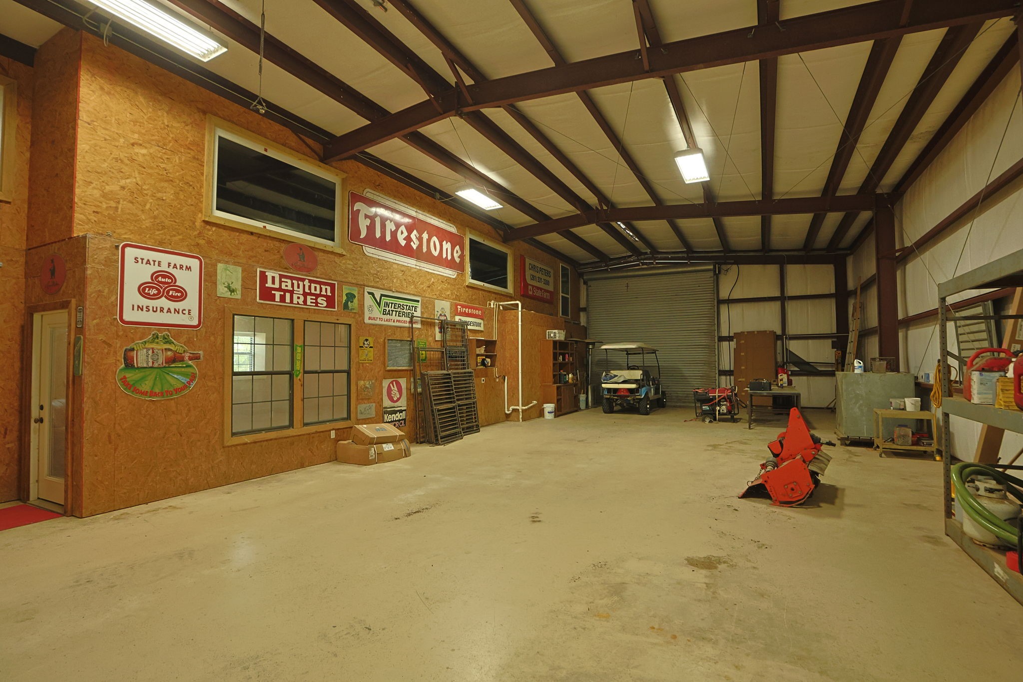 Spacious, industrial-style workshop with high ceilings, ample storage, and vintage signage, perfect for automotive enthusiasts or large-scale projects.
