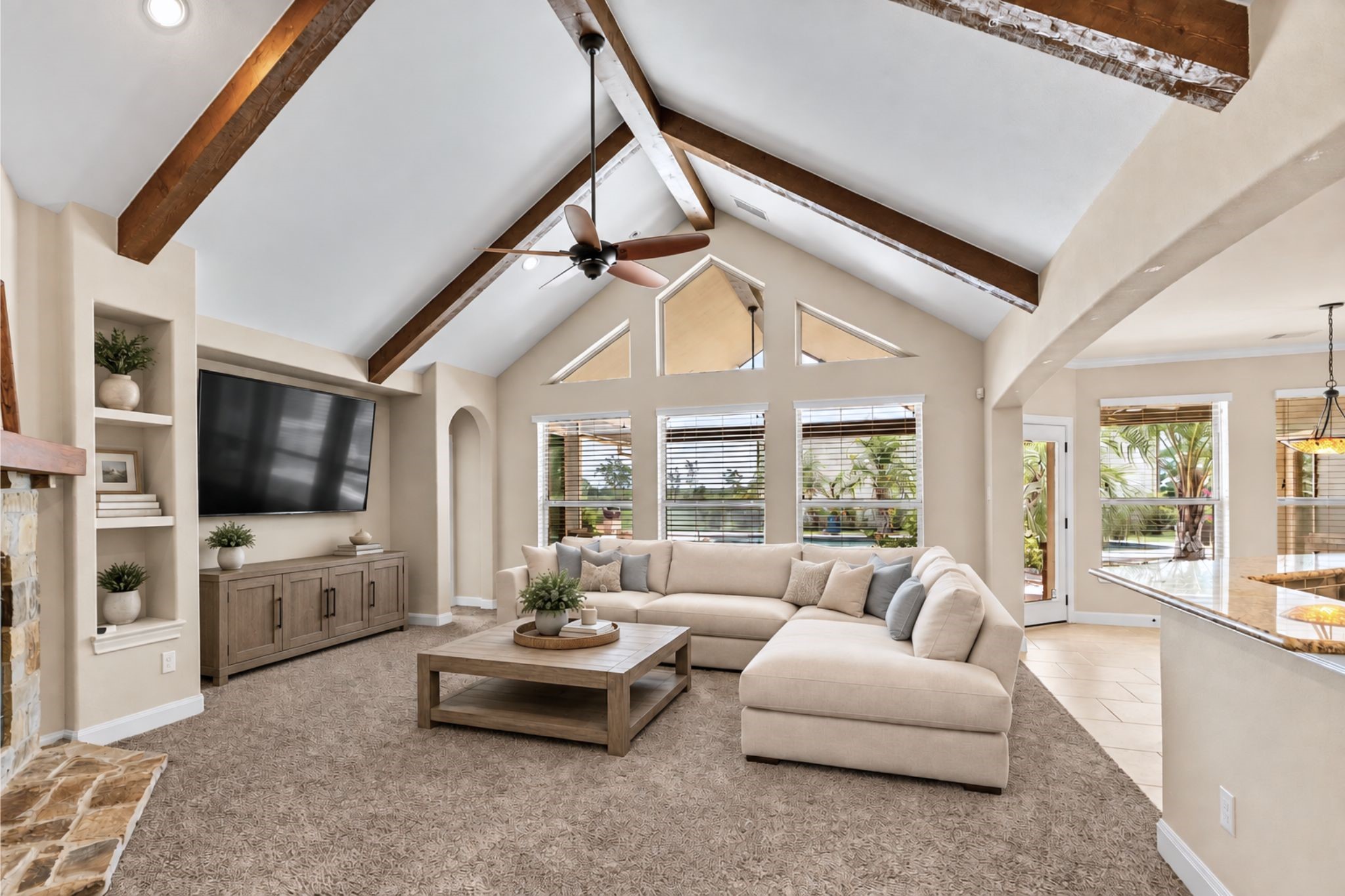 Spacious living room featuring vaulted ceilings with exposed beams, a cozy fireplace, and abundant natural light from large windows. **VIRTUAL STAGING, DECOR ONLY HAS BEEN ADDED**