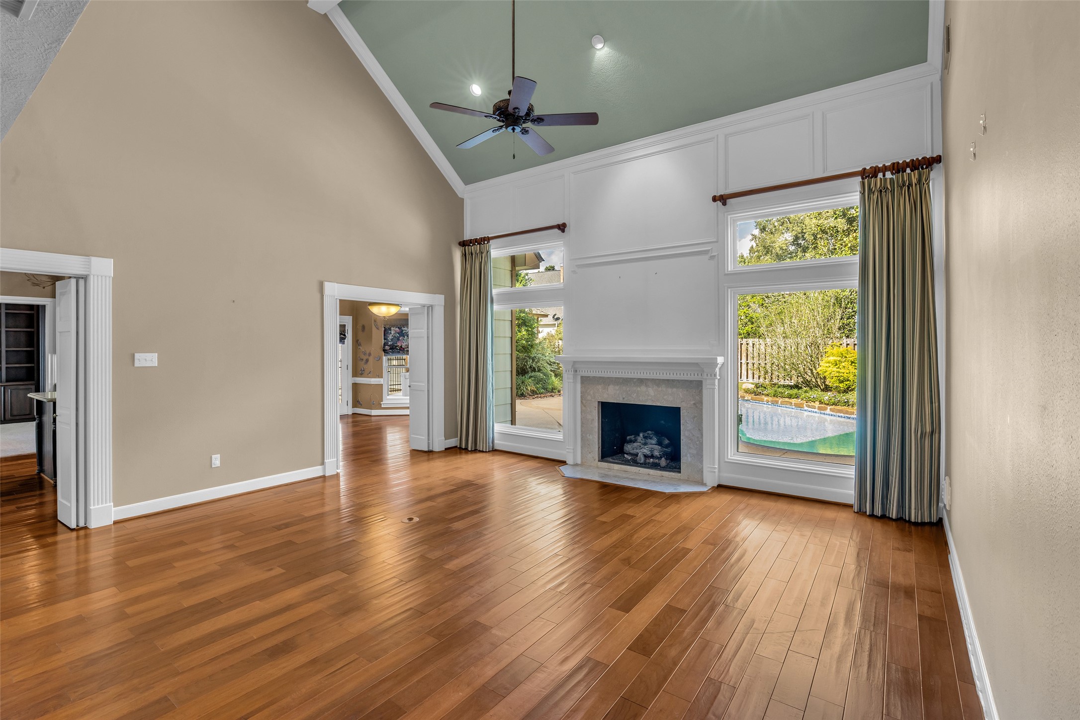Two-story living room with fireplace and views of the private pool.