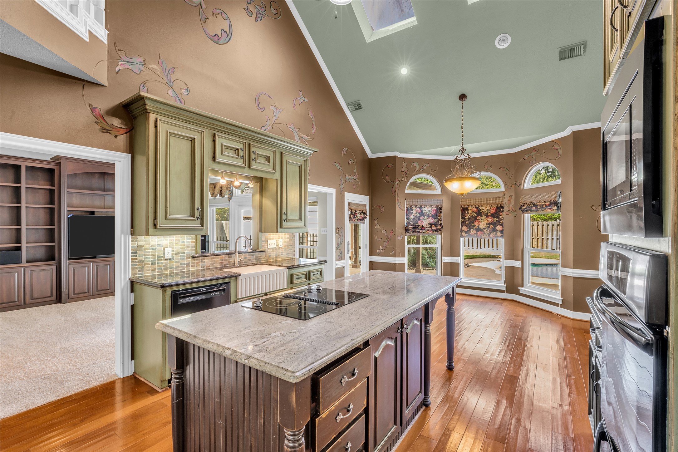 Two-story kitchen with large center island, breakfast area, and skylights.
