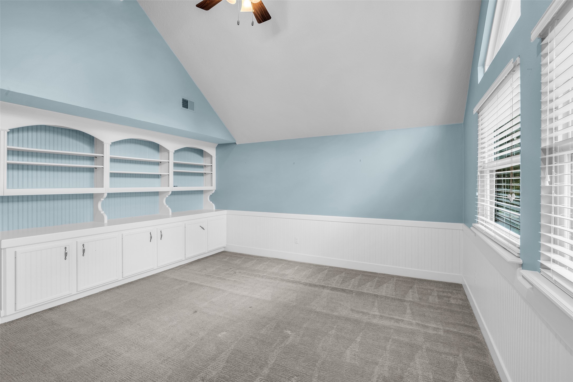 Upstairs game room with vaulted ceiling and built-in shelving.