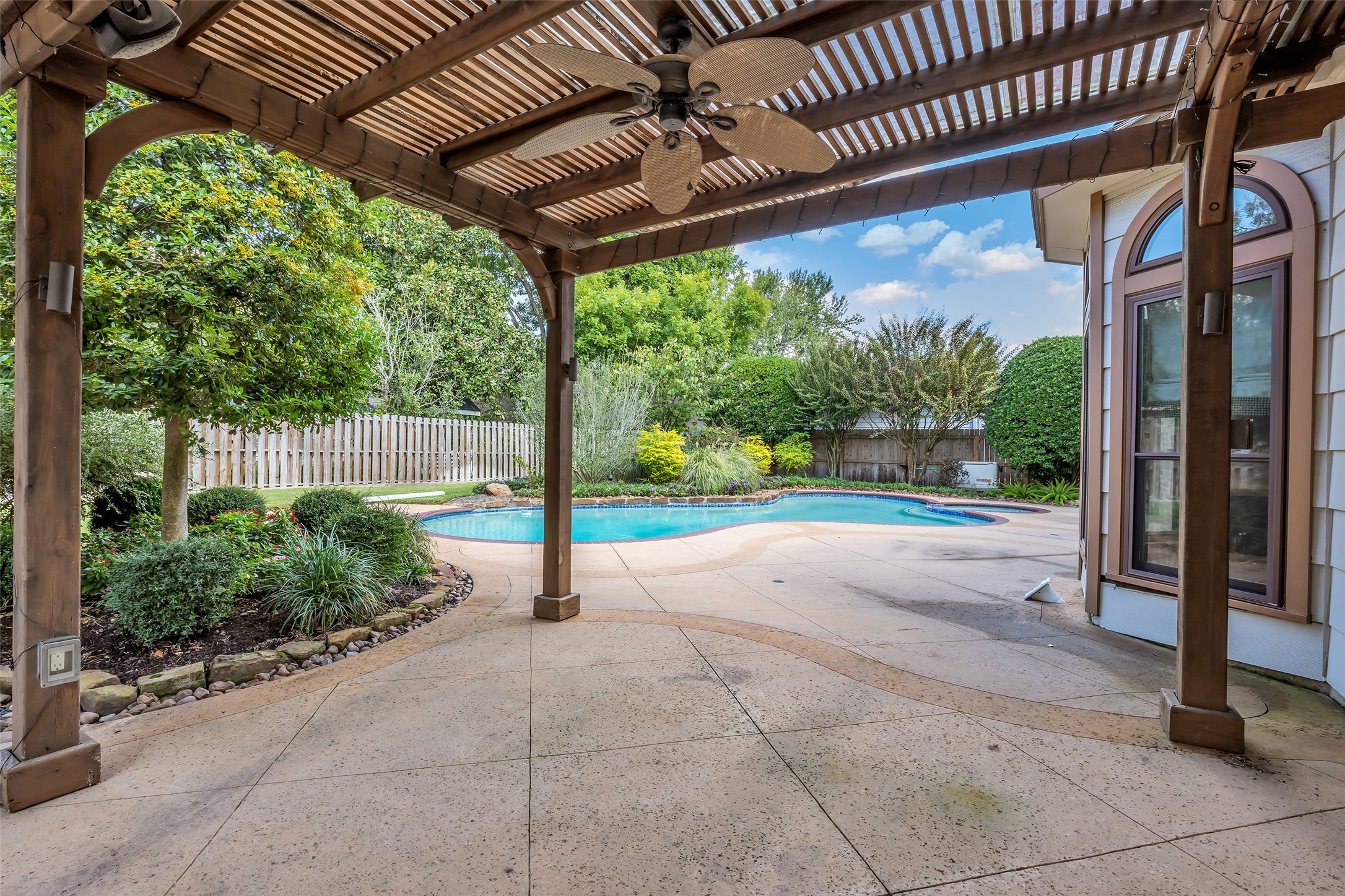 Wood pergola with ceiling fan and string lighting overlooking the pool.