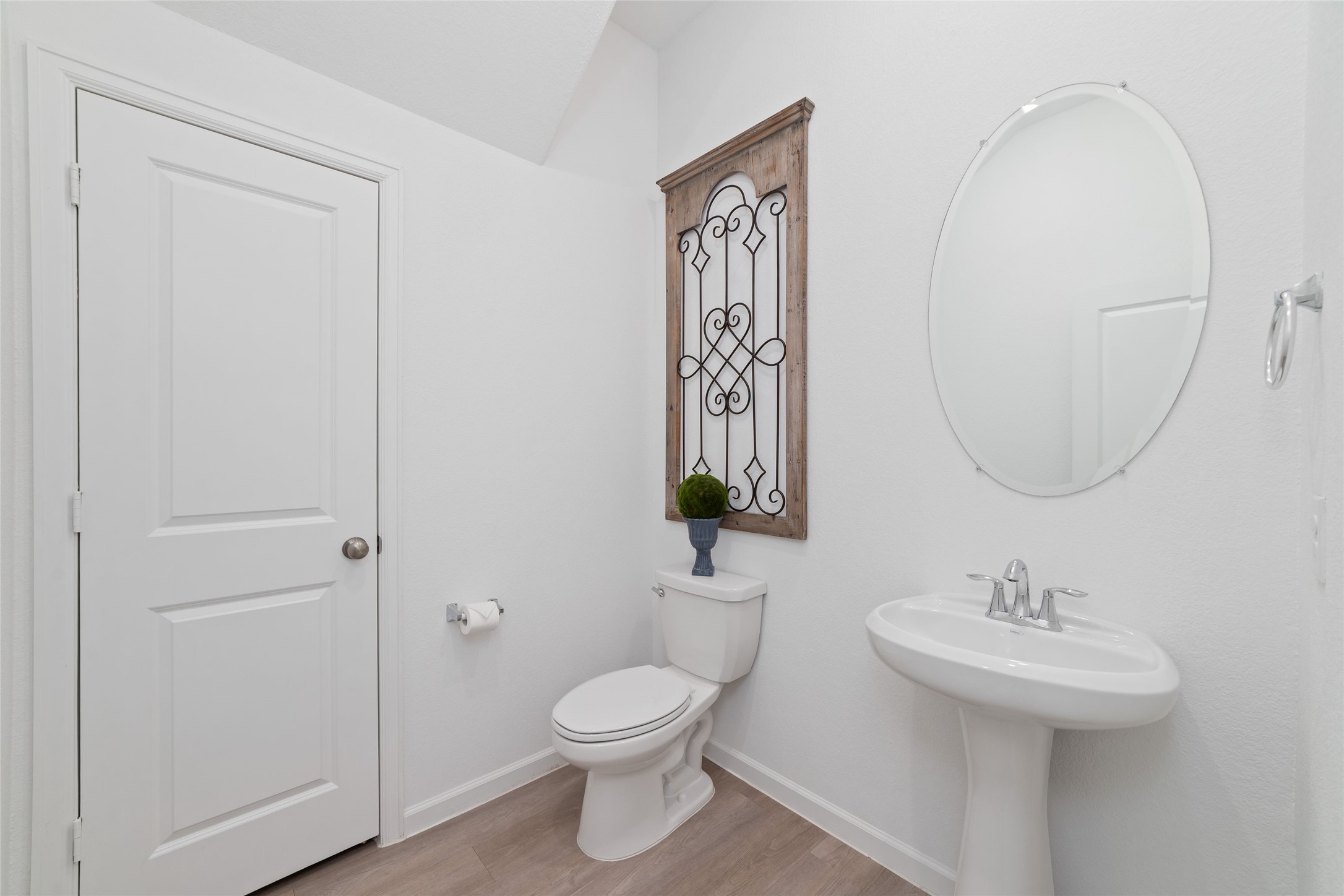 The convenient main-level half bathroom features a pedestal sink, decorative mirror, and neutral finishes, providing easy access for guests and everyday use.
