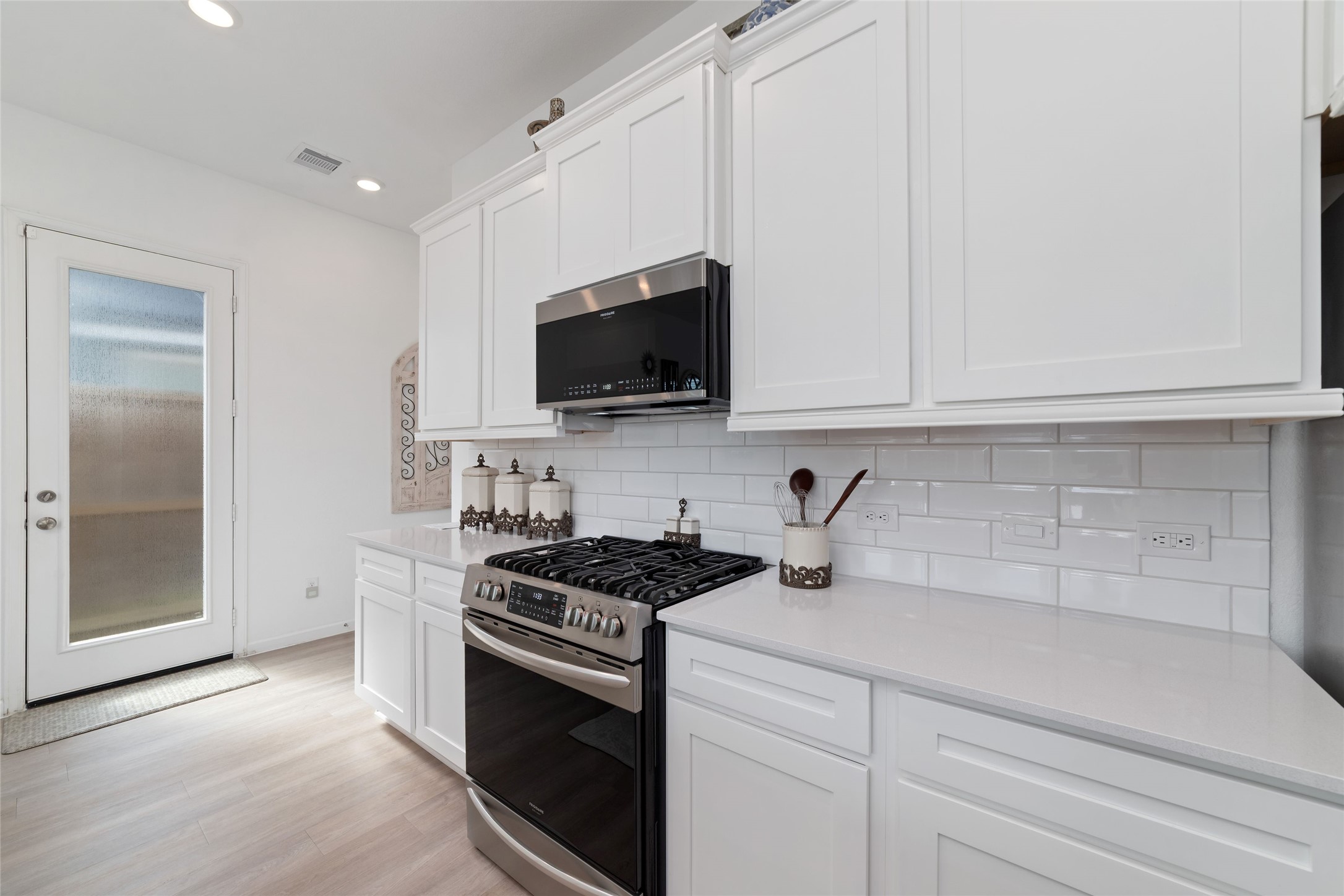 Another view of the kitchen highlights the abundant cabinetry, neutral finishes, and convenient access to the adjacent dining and living areas.