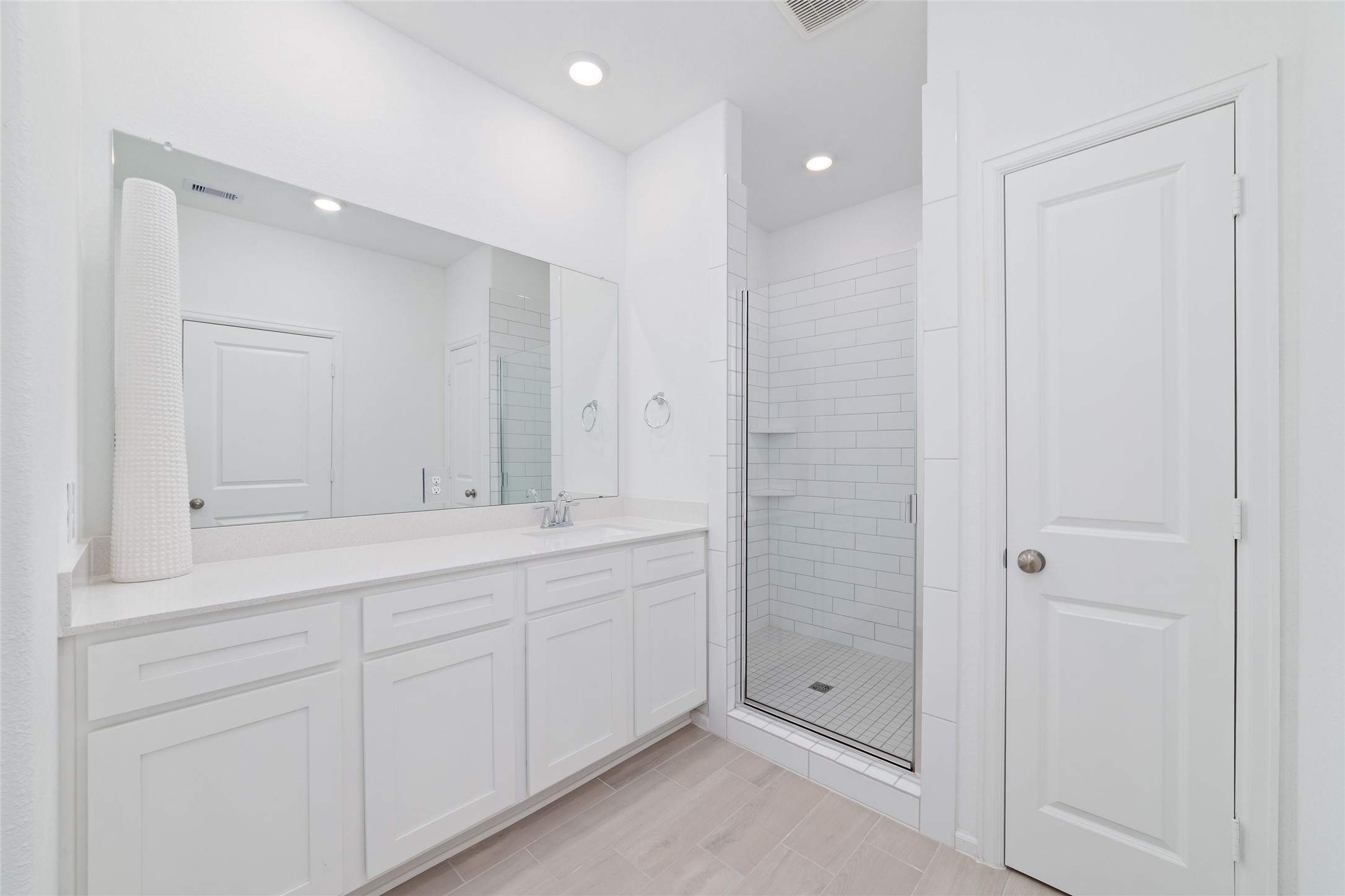 The primary bathroom features a spacious vanity with white cabinetry, generous counter space, and a separate walk-in shower.