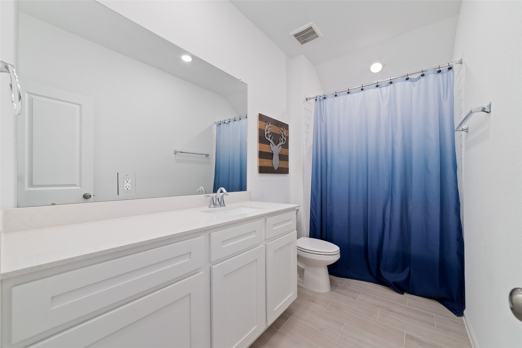 The secondary full bathroom features a shower/tub combination, white vanity cabinetry, and a functional layout.