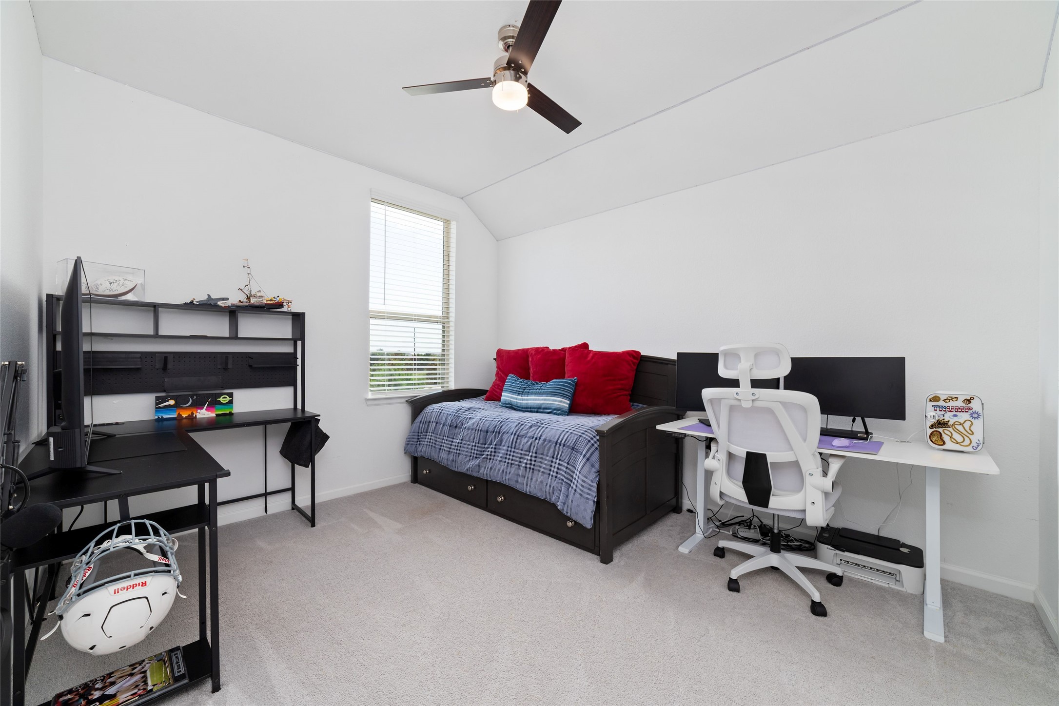 A secondary bedroom features plush carpeting, neutral finishes, and a large window, offering a comfortable space for family members or guests.