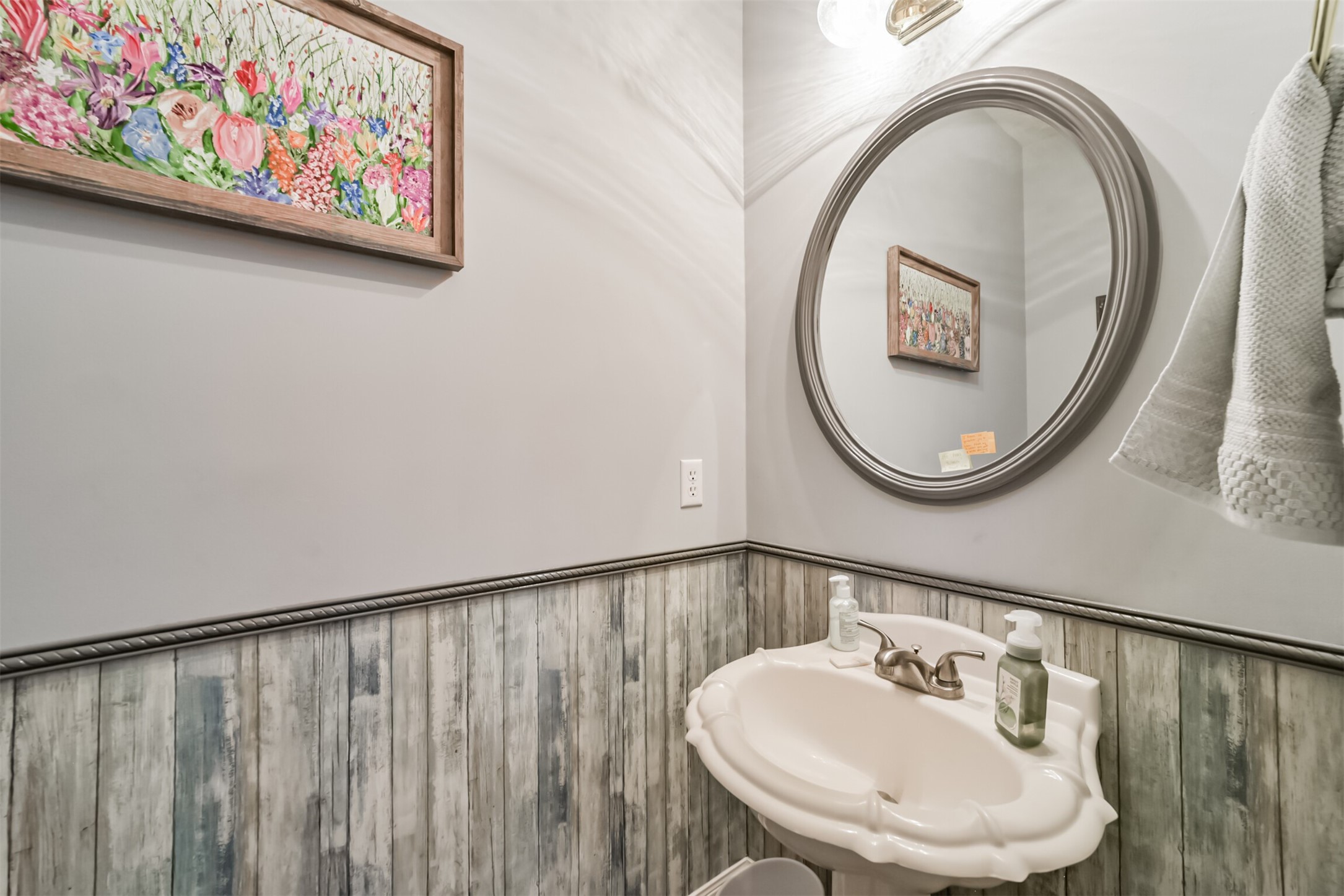 The downstairs half bath features a pedestal sink and Beadboard wall accents.