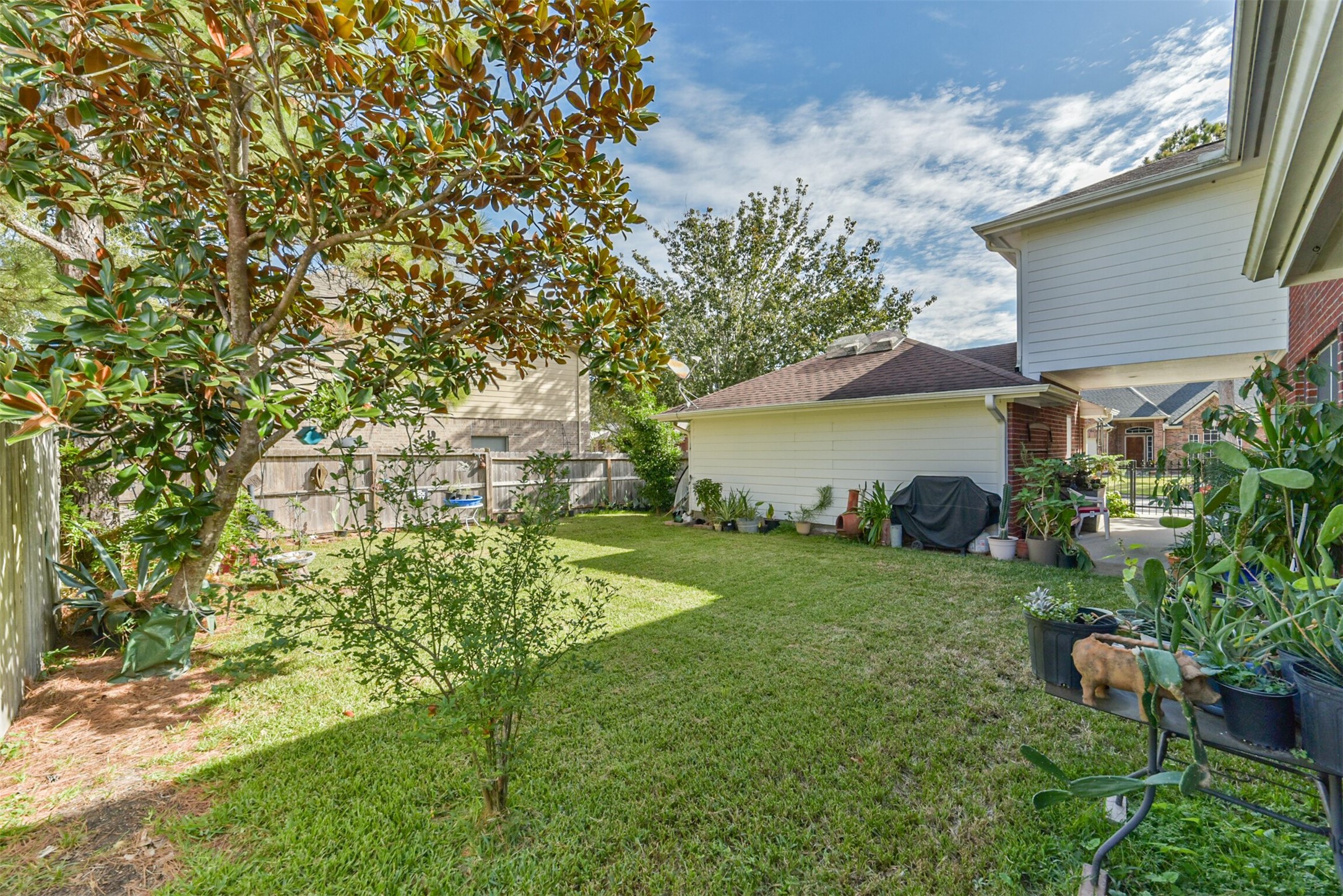 A private backyard enclosed by a fence, featuring a patio nestled between the garage and the house.