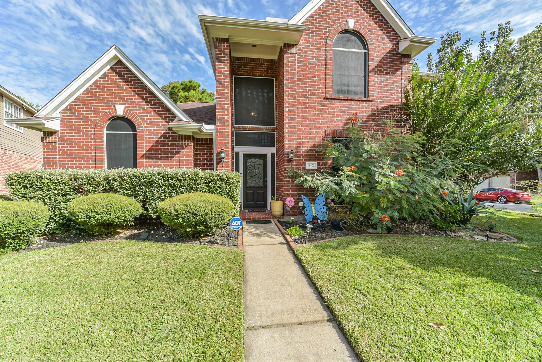 A two-story covered porch surrounded by lush, verdant landscaping.