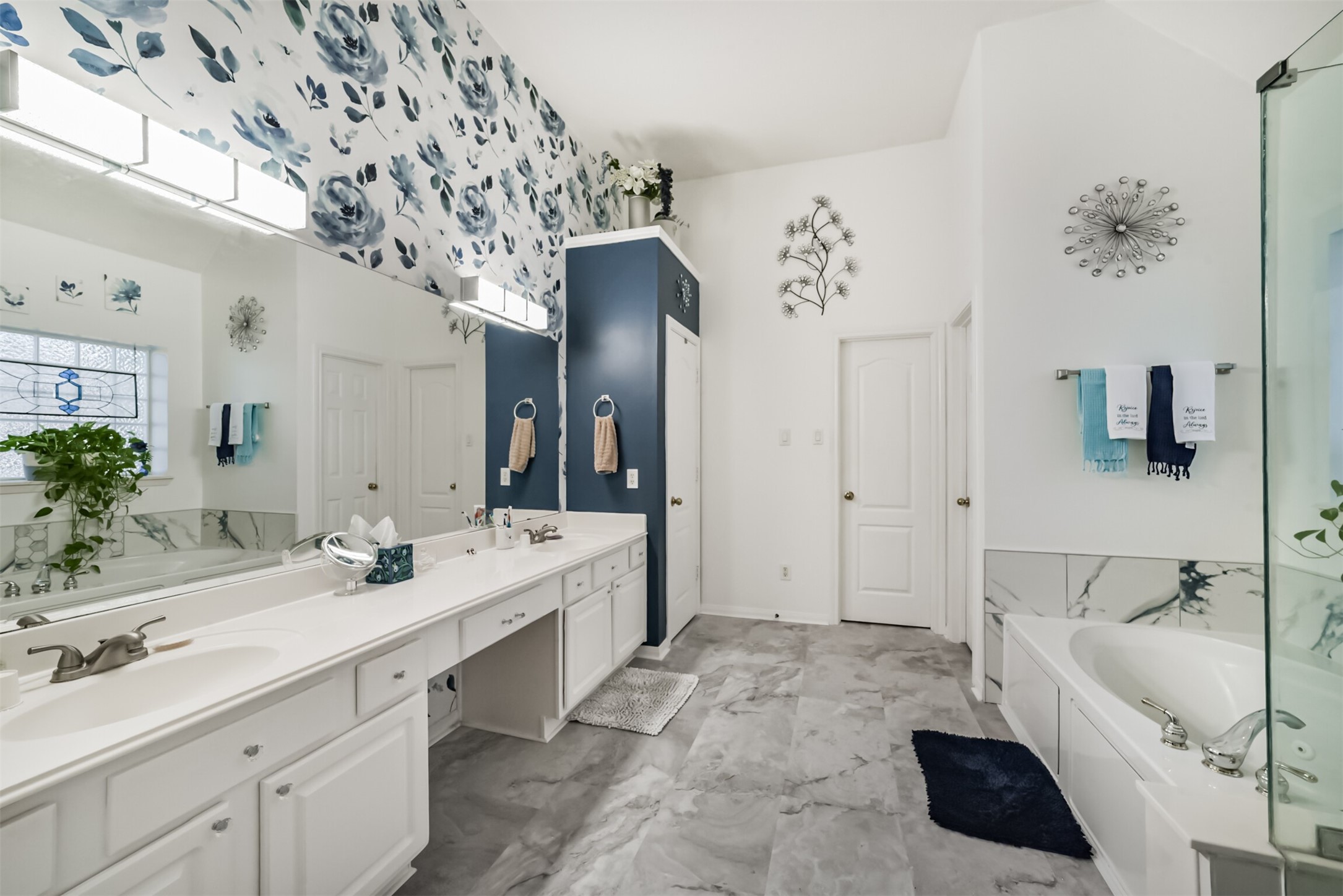 The primary bathroom features a cultured marble vanity with dual sinks and a built-in makeup desk, along with a private water closet and a jetted soaking tub with a separate shower.