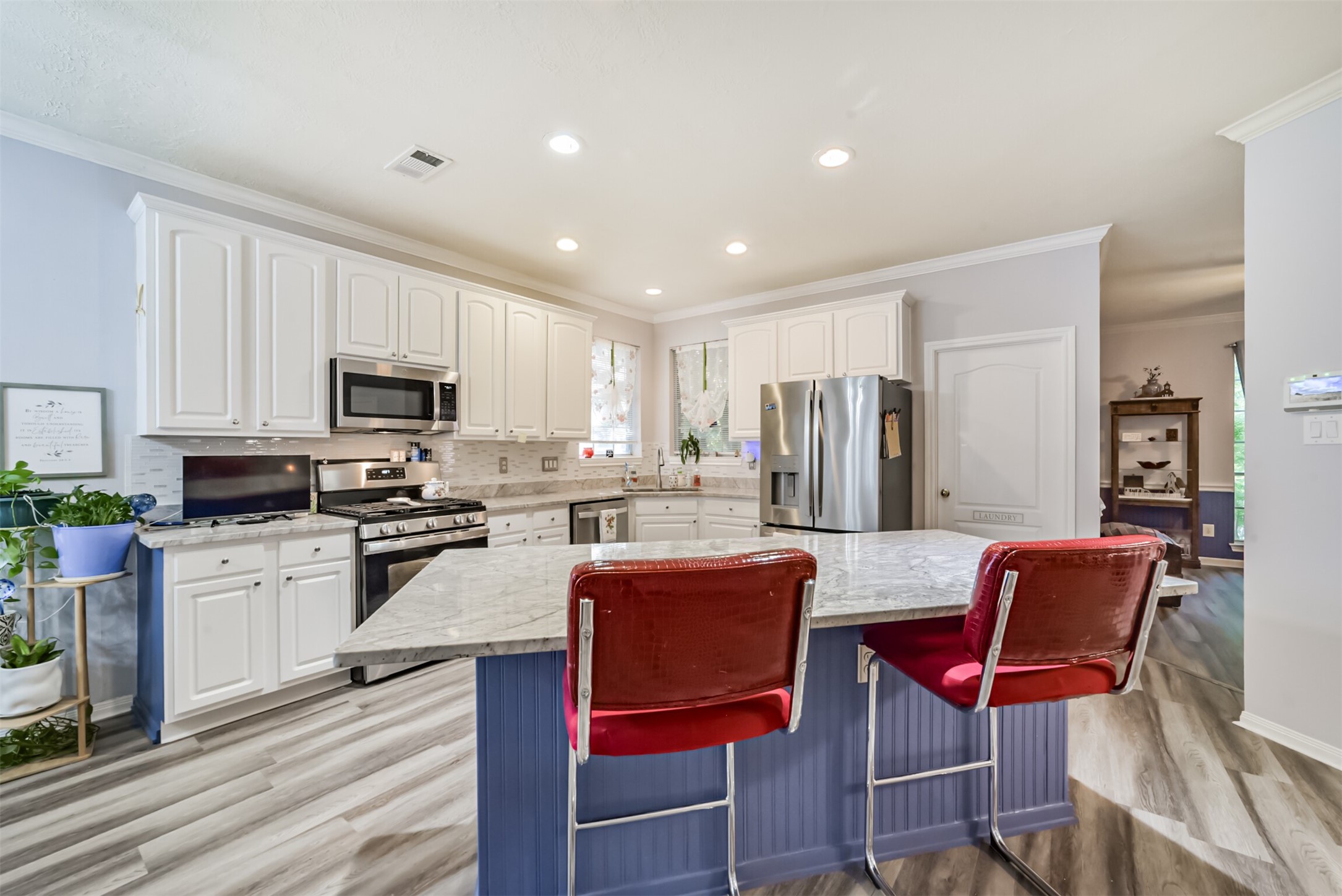 A center island with a breakfast bar and granite countertops, complemented by recessed lighting.