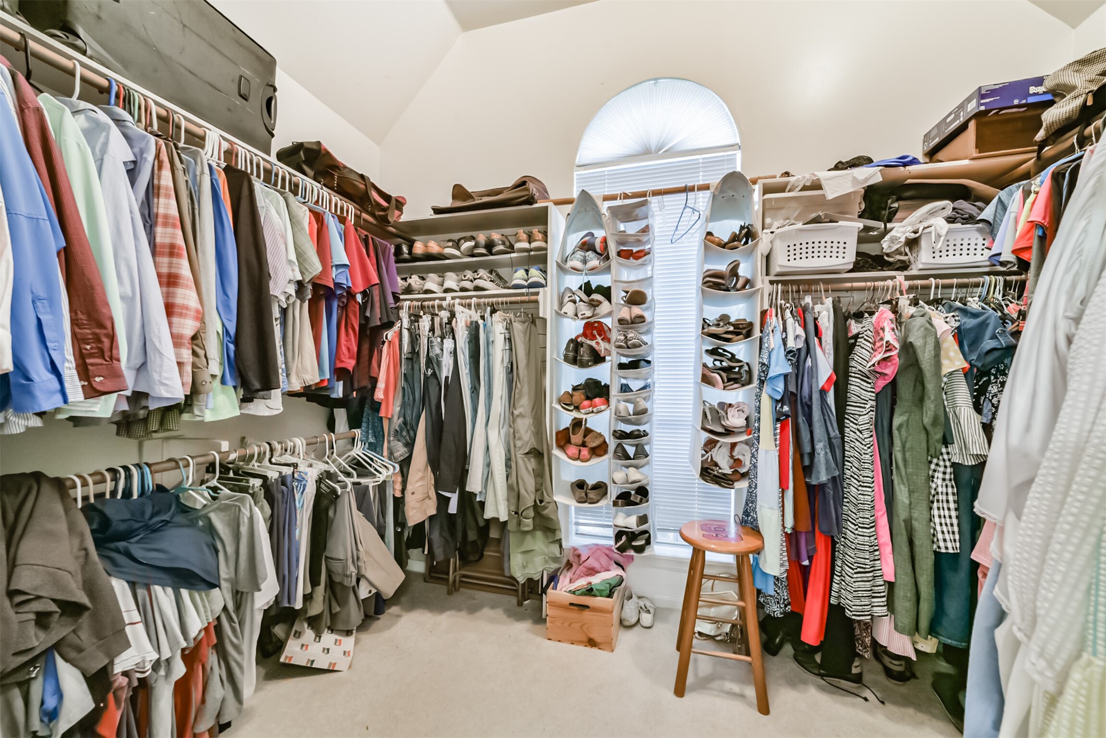 The primary bedroom offers abundant storage, including shoe racks, wooden dowels, and built-in shelving.