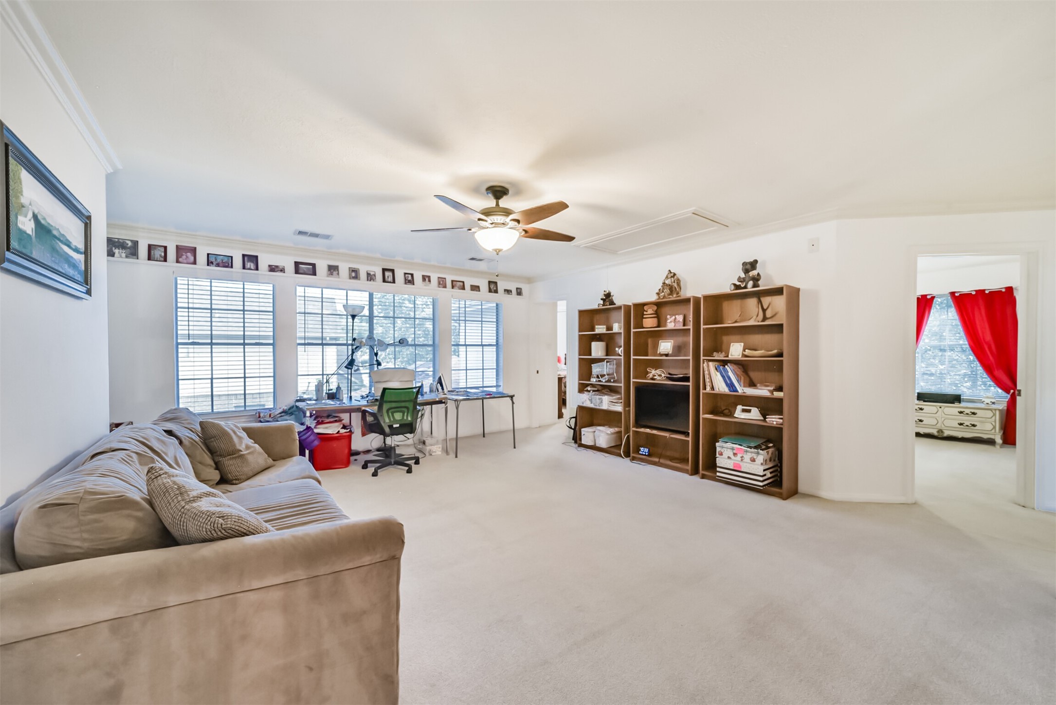 Upstairs, the game room is bright and airy, with a wall of windows and a ceiling fan with a built-in light fixture.