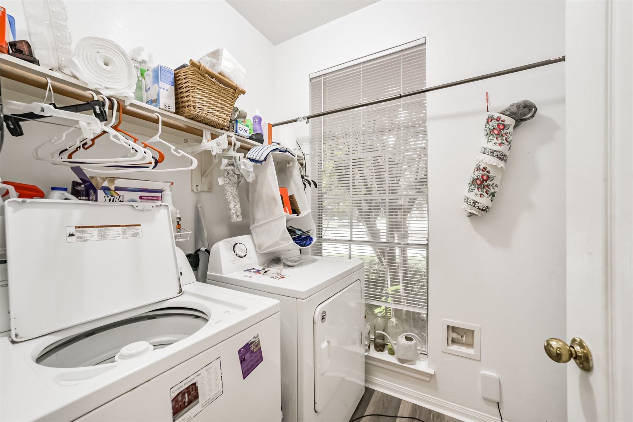 A laundry room with a storage shelf, a wooden drying rod, and a window.