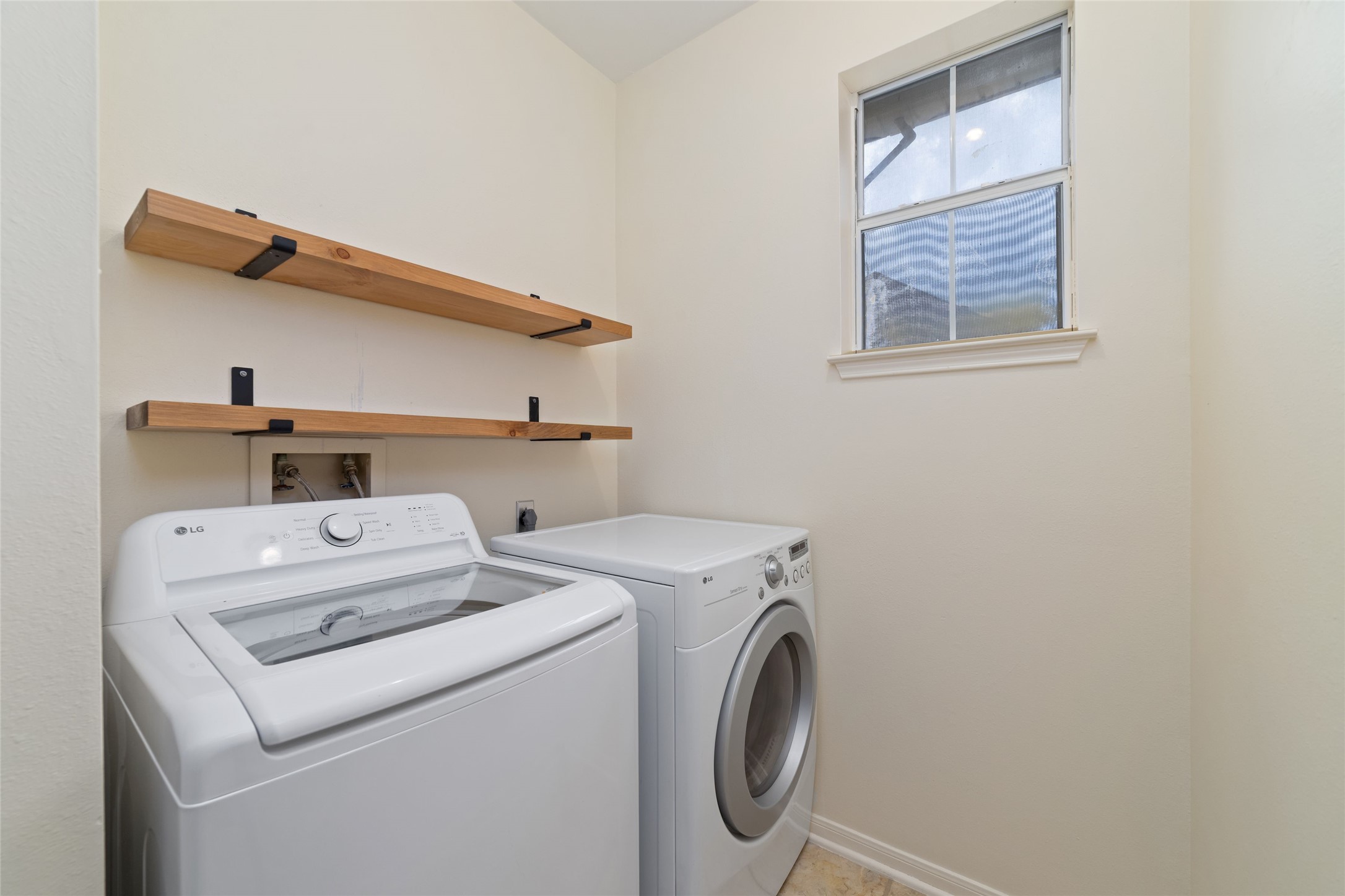 Interior utility room with washer and dryer space plus open shelving for storage.