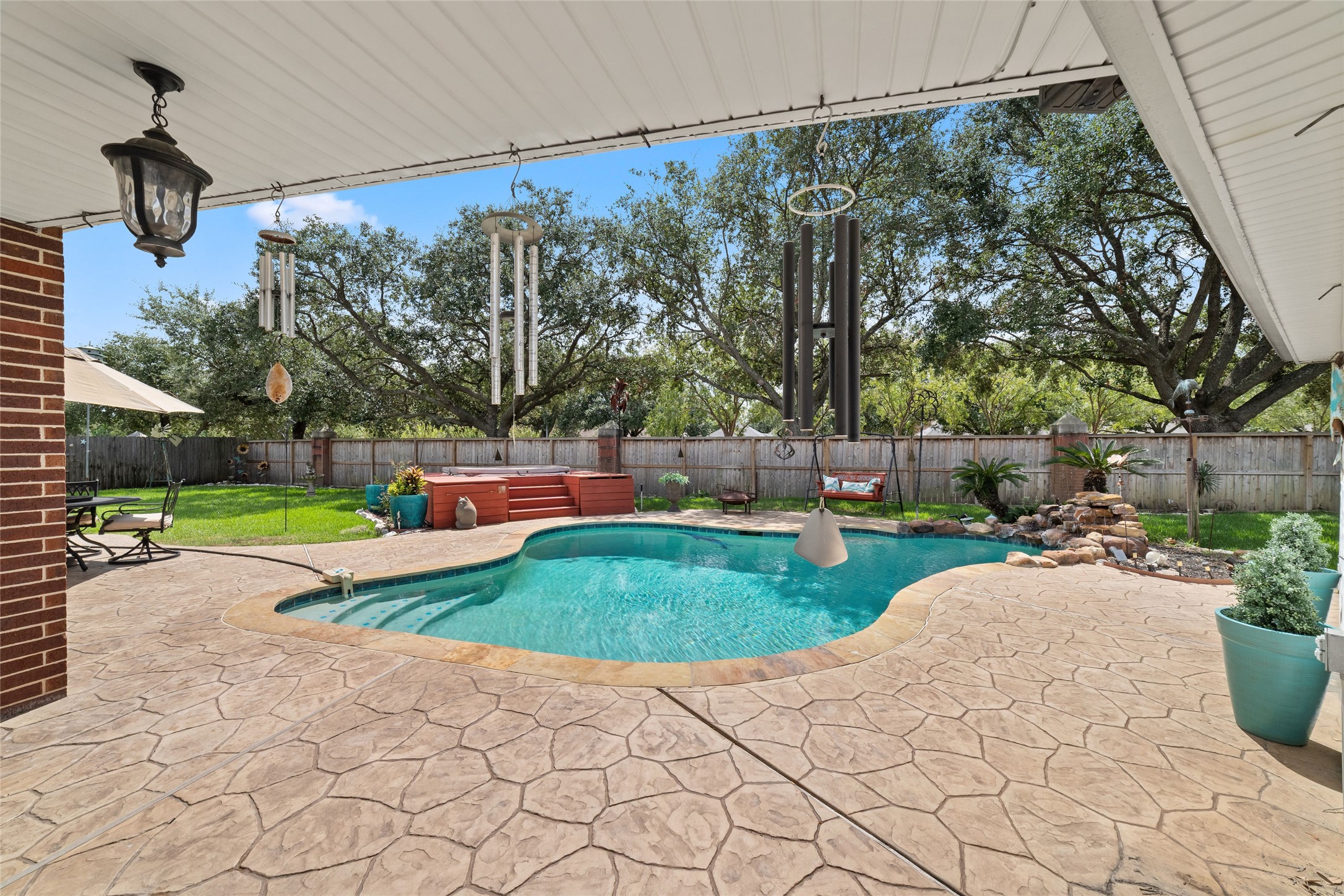 Covered back patio overlooking the private pool and tree-lined backyard.