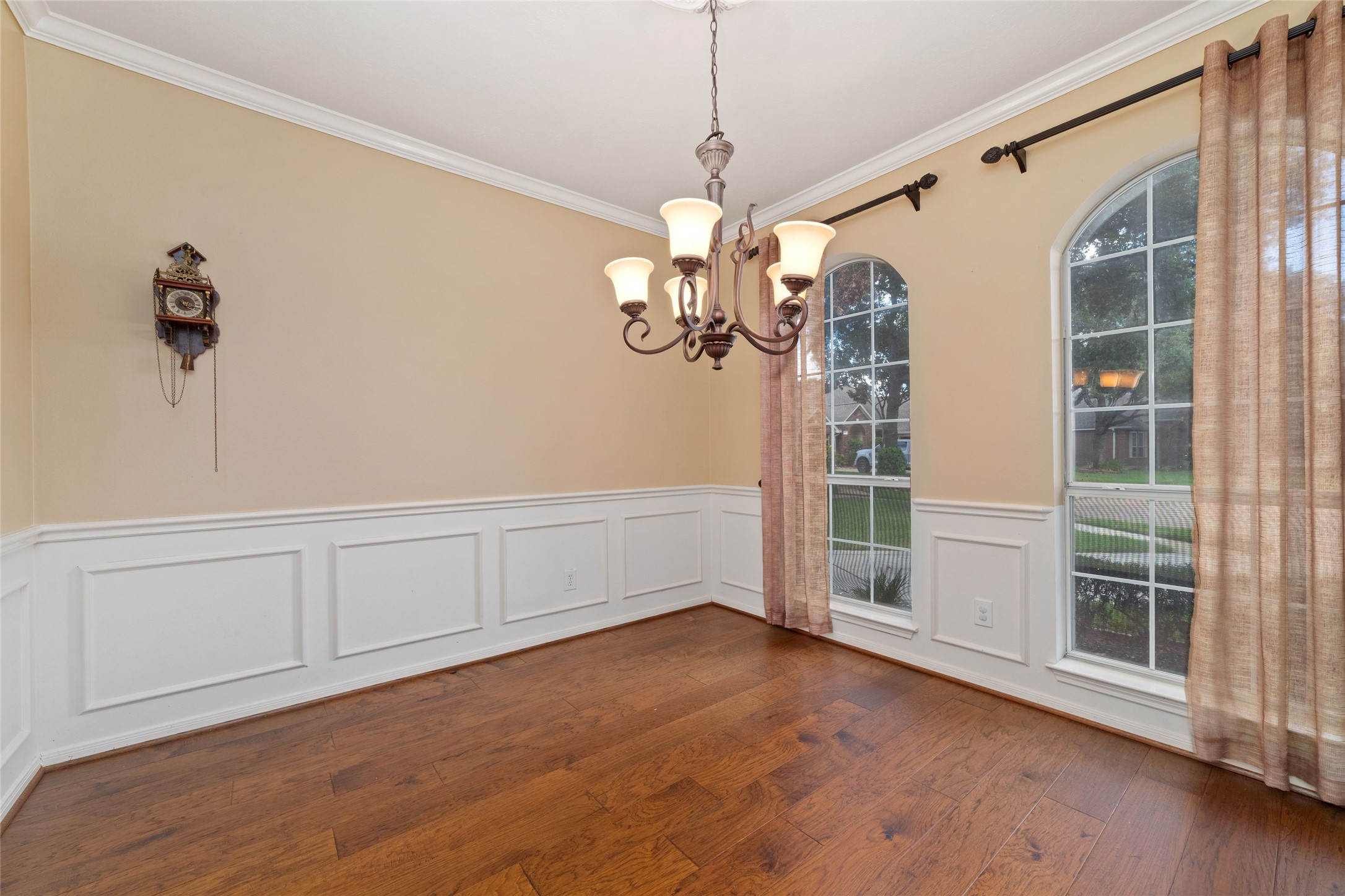 Formal dining room with wood flooring, decorative wall molding, crown molding, and tall windows.