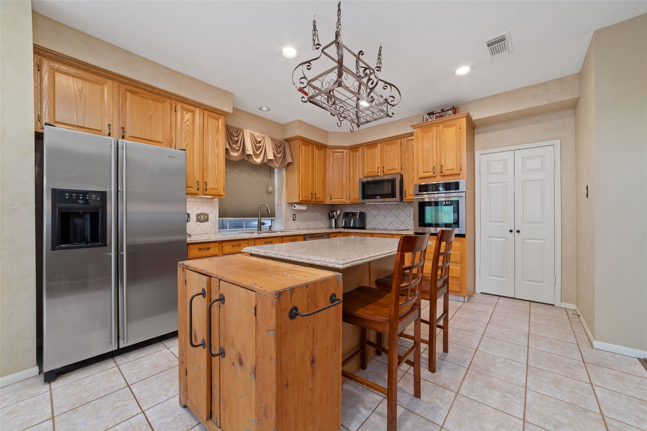Spacious island kitchen with granite counters, stainless-steel appliances, breakfast-bar seating, and abundant cabinetry.