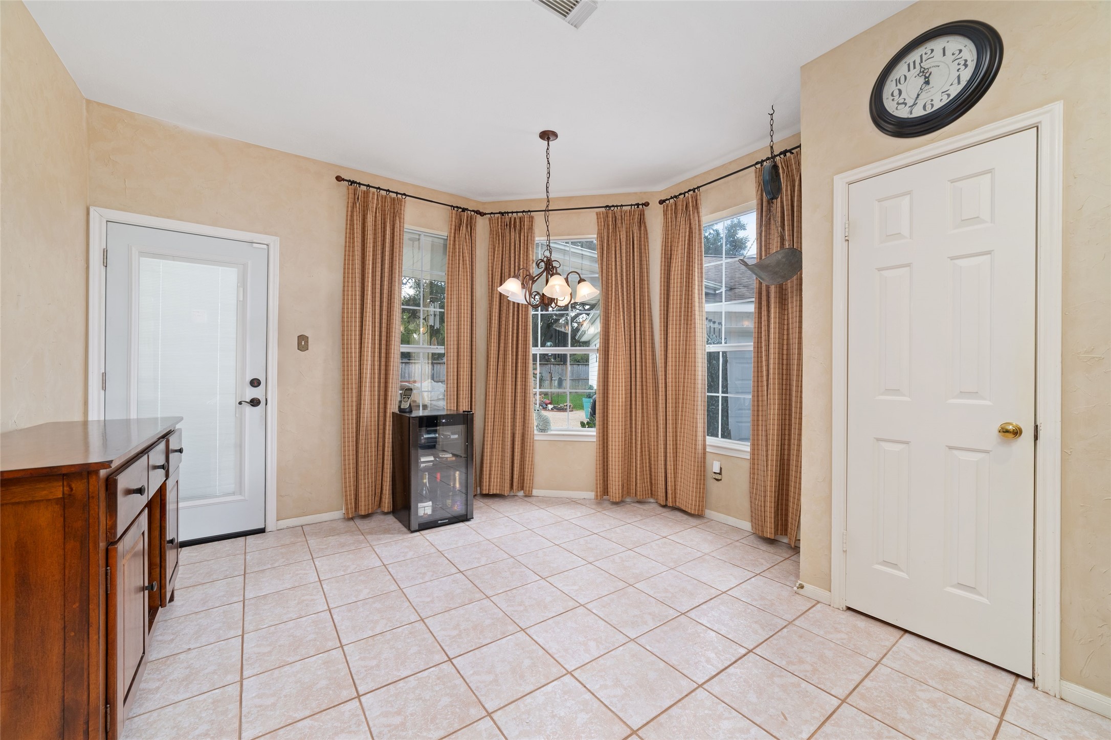 Natural light filled breakfast room with tile flooring, multiple windows, backyard access, and nearby pantry storage.