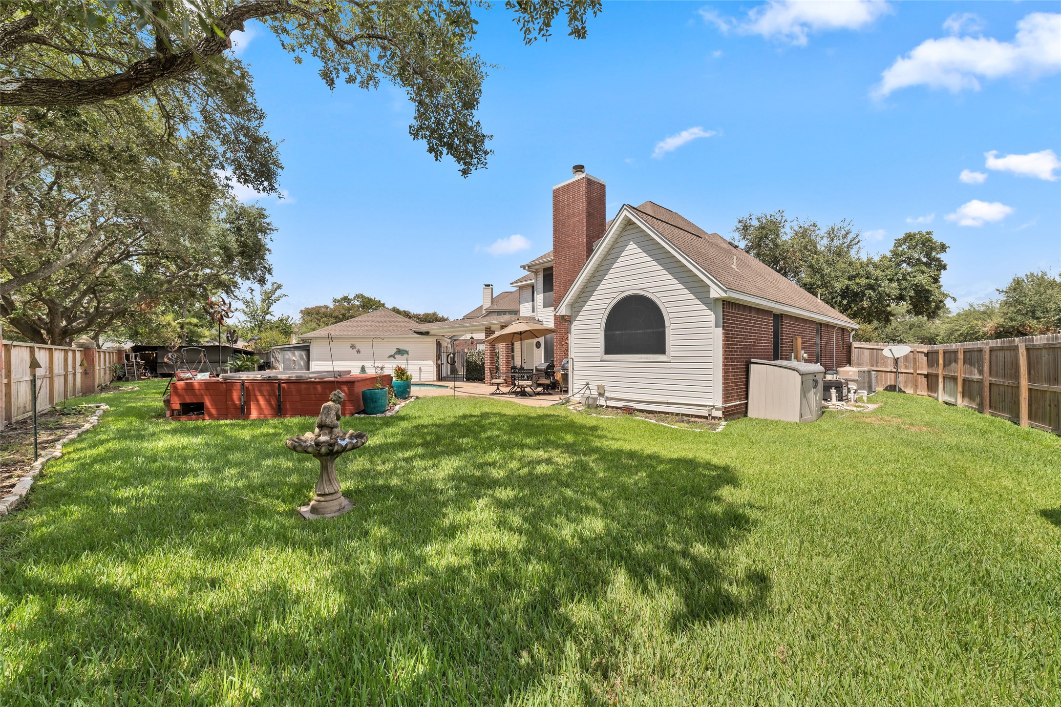 Expansive fenced backyard with mature shade trees and substantial green space beyond the pool area.