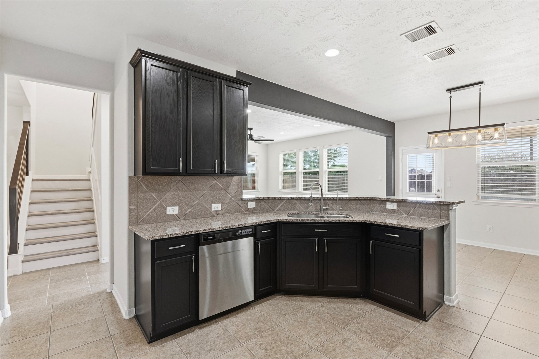 A double-basin sink with high-arc faucet overlooks the adjoining living area, while stainless steel appliances include a built-in dishwasher.