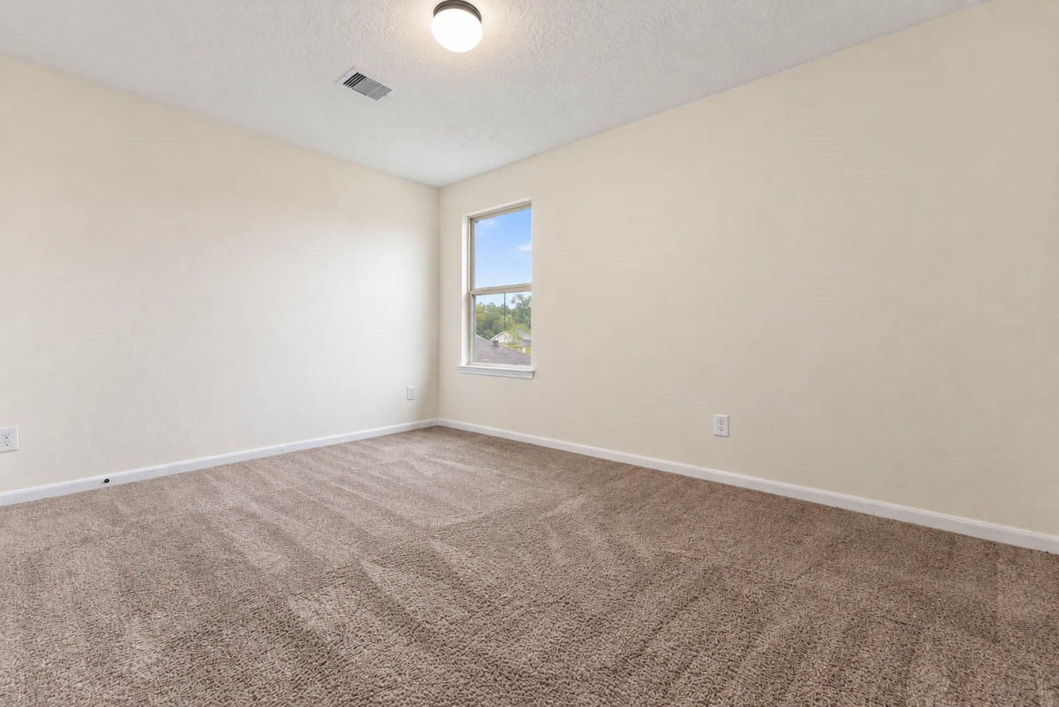 This generously sized secondary bedroom offers plush carpeting, a soothing neutral color palette, & a large window that welcomes natural light.