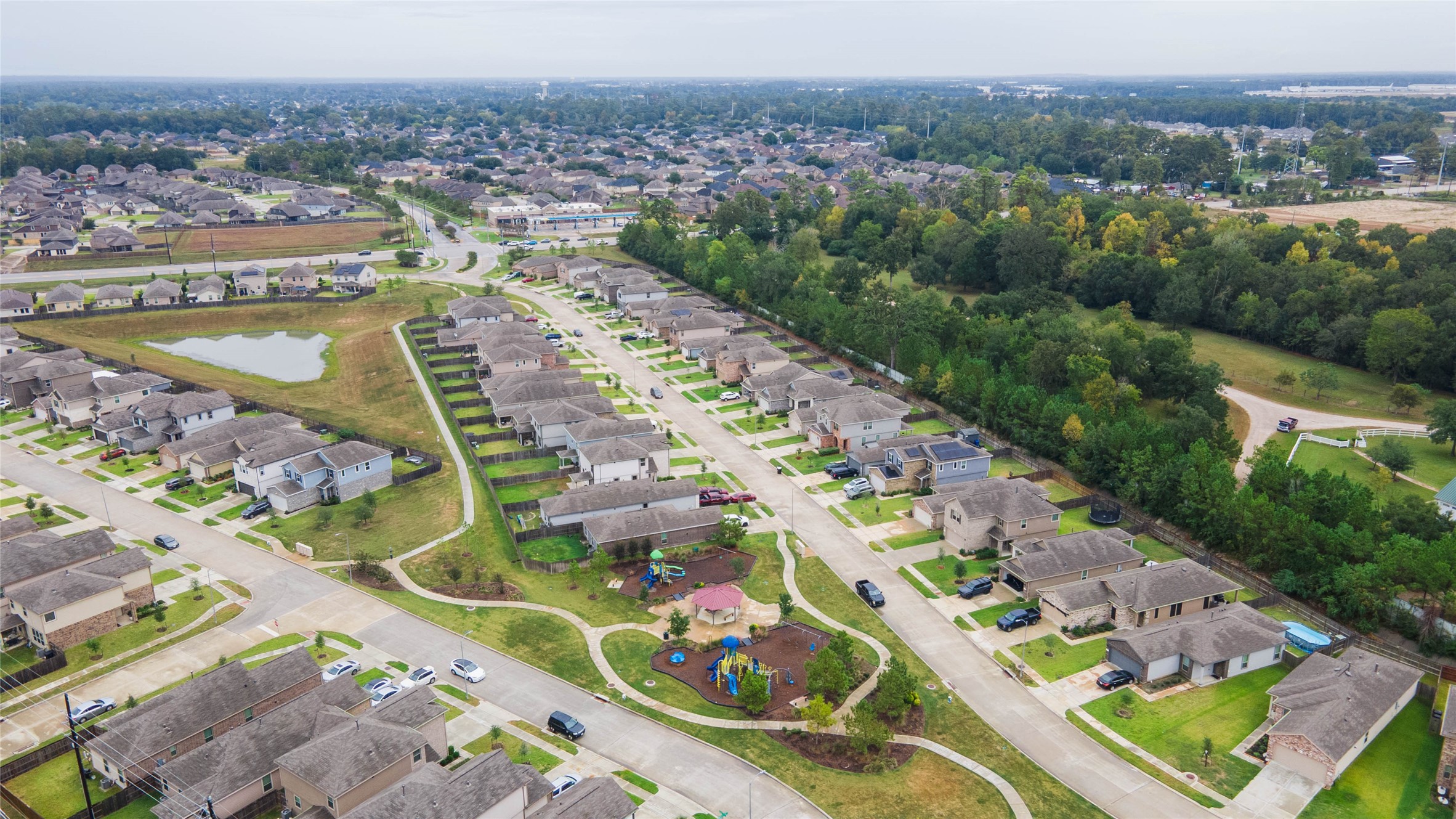 This elevated view showcases attractive residential streets framed by a beautiful backdrop of mature trees, offering a peaceful atmosphere with community recreational spaces nearby.