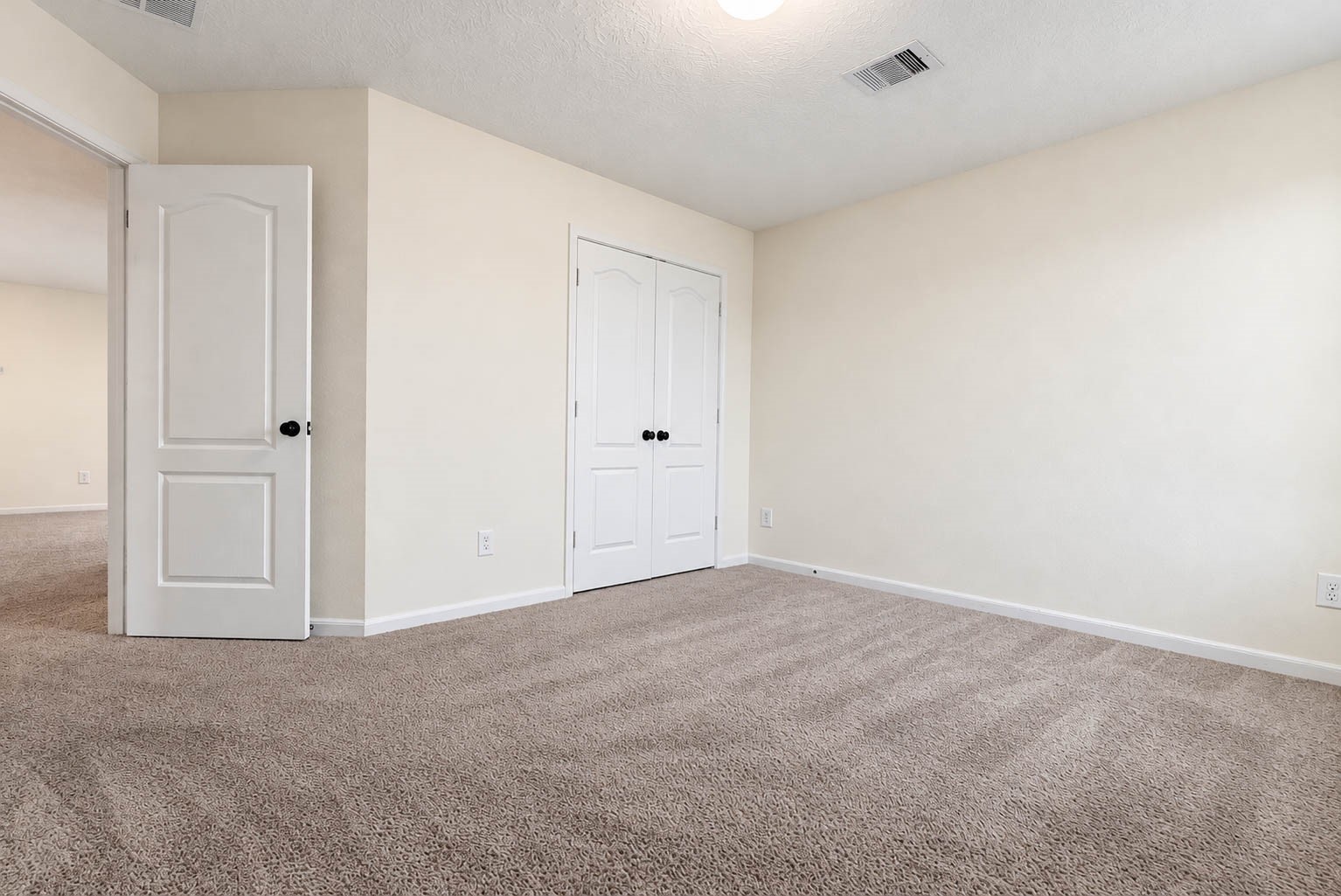 Another view of this inviting secondary bedroom highlights its comfortable proportions & ample wall space for arranging furniture. A spacious double-door closet provides ample storage space, making this room both comfortable & functional.