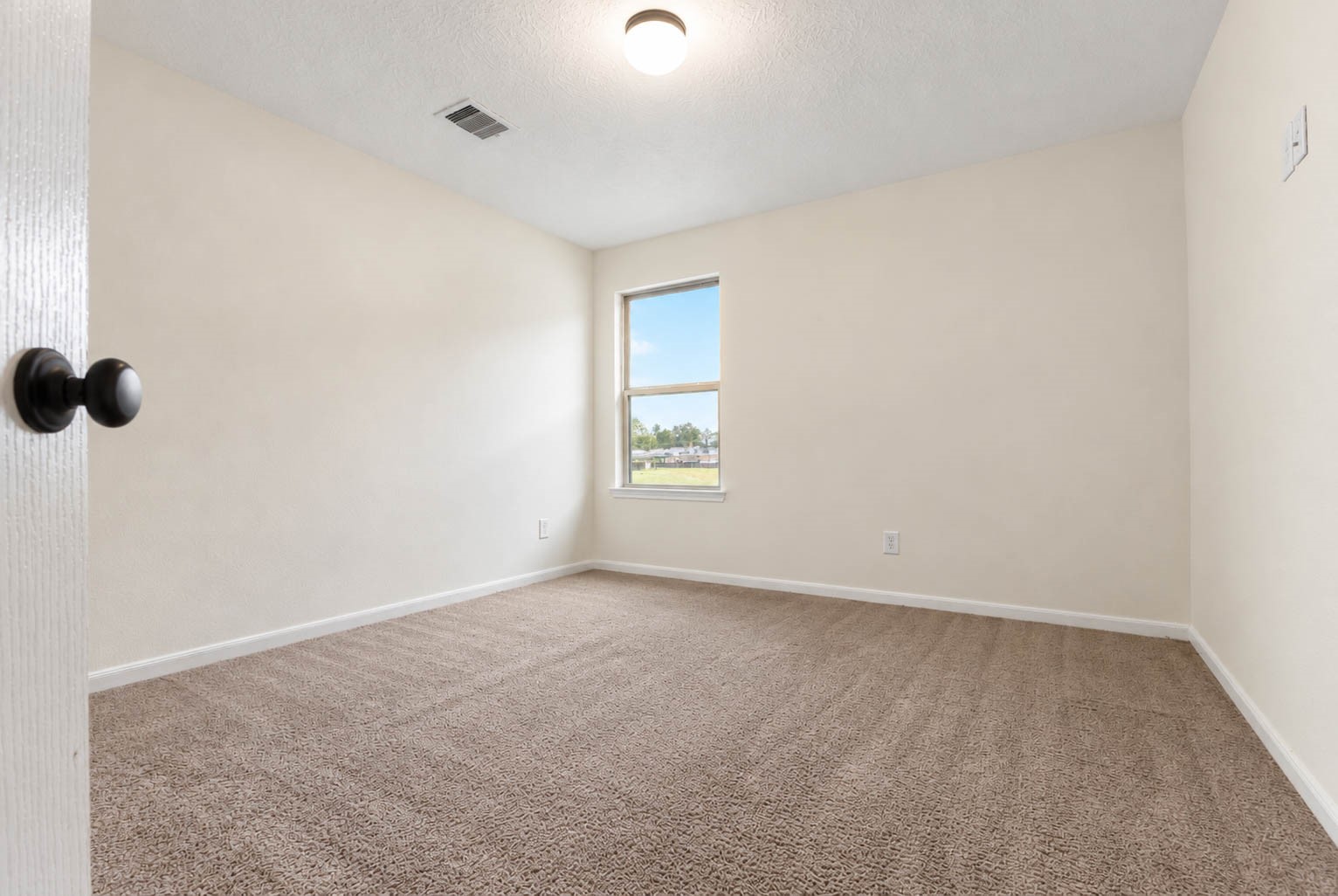 This final secondary bedroom offers plush carpeting, neutral finishes, & a large window that fills the space with natural light.