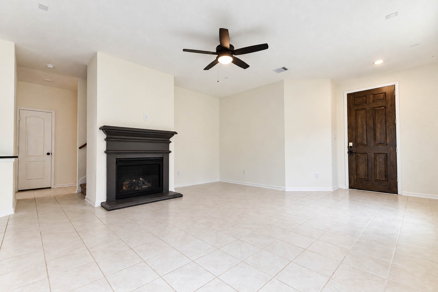 The spacious open-concept family room exudes warmth & elegance, showcasing beautiful tile flooring, soaring ceilings, recessed lighting, & a stylish ceiling fan. A soothing neutral color palette enhances the bright, airy atmosphere while providing a timeless backdrop to complement any decorating style.