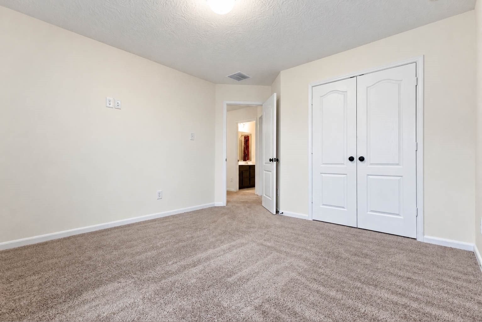Another view of this spacious secondary bedroom highlights its generous floor space, double-door closet, & soothing neutral color palette. The versatile layout offers endless possibilities for furniture arrangements, allowing you to personalize the space to suit your needs.