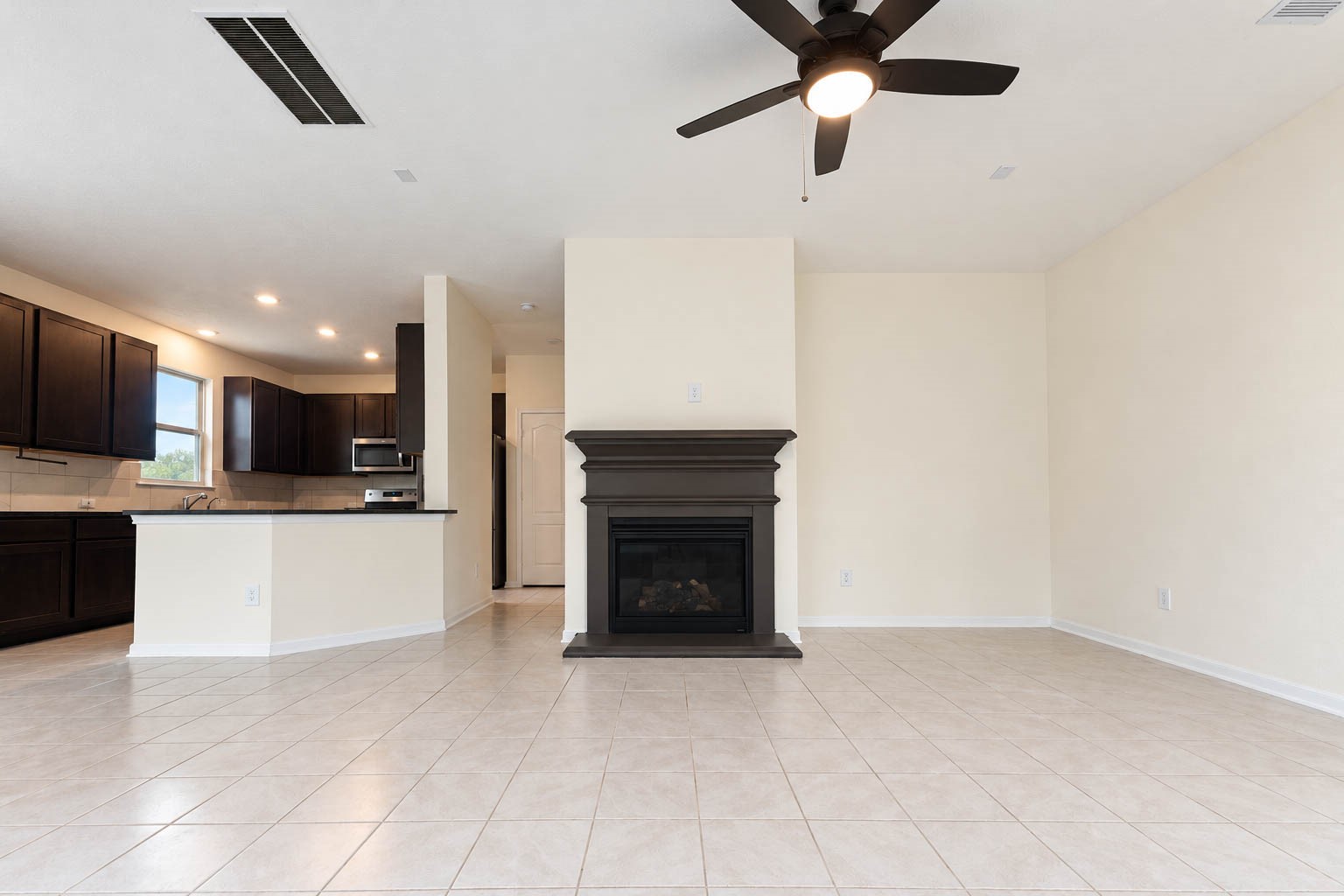 A beautiful gas-log fireplace with a rich, dark mantel creates a stunning focal point, bringing warmth, timeless charm, & an inviting ambiance to the spacious family room.