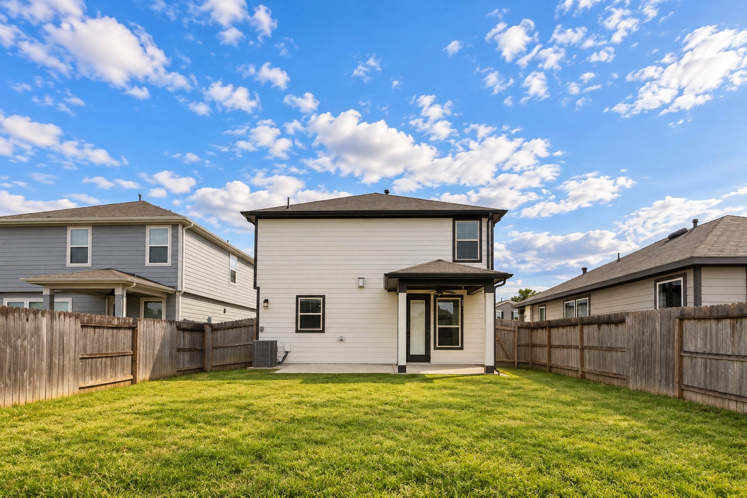 This beautiful view from the rear property line showcases the home's attractive two-story exterior, spacious covered patio, & expansive grassy backyard, offering a wonderful setting for outdoor relaxation & entertaining.