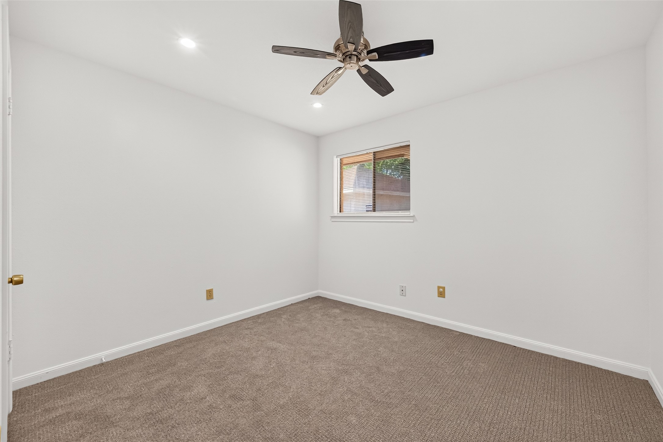 Freshly painted secondary bedroom featuring neutral carpeting, recessed lighting, and a modern ceiling fan creating a bright and comfortable space.