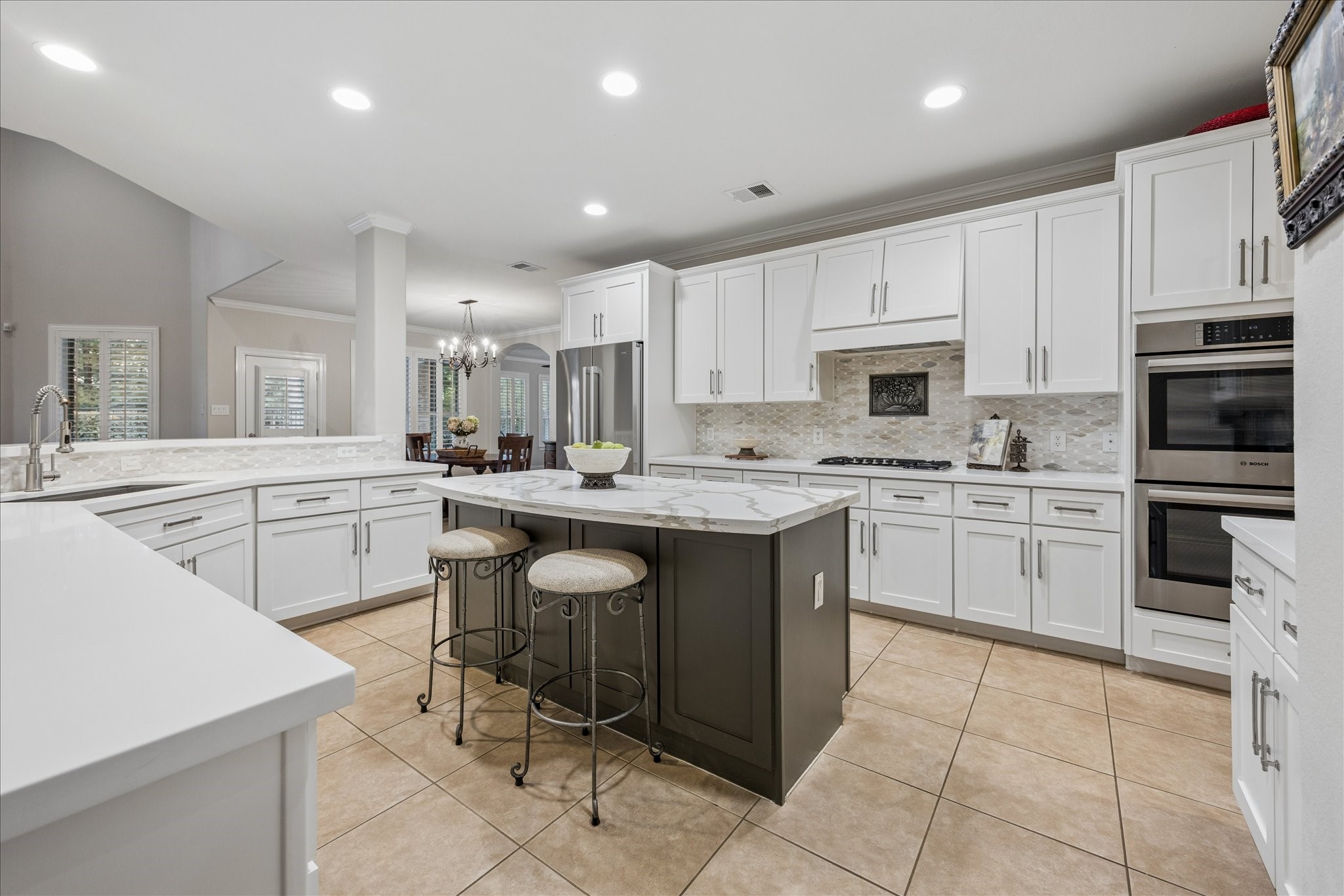 Updated in 2020, this inviting island kitchen features double ovens, quartz countertops, stylish backsplash, and updated hardware; seamlessly flowing into the adjoining living spaces. Updated in 2020, this inviting island kitchen features double ovens, quartz countertops, stylish backsplash, and updated hardware; seamlessly flowing into the adjoining living spaces.
