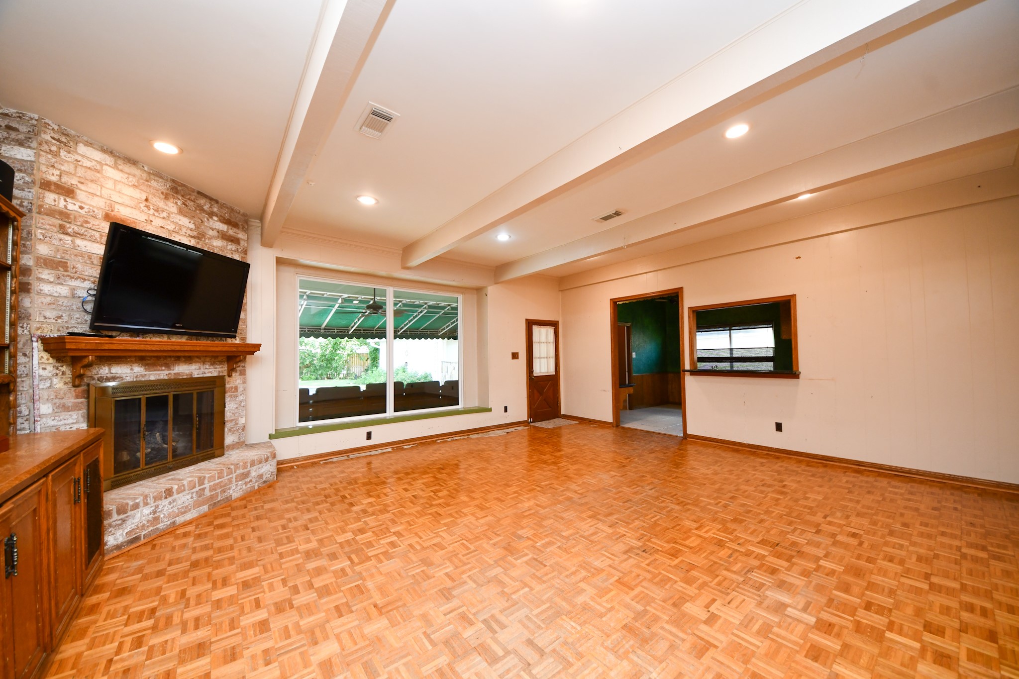 Spacious family room with beamed ceiling, brick fireplace and an abundance of room to reimagine the space. Spacious family room with beamed ceiling, brick fireplace and an abundance of room to reimagine the space.